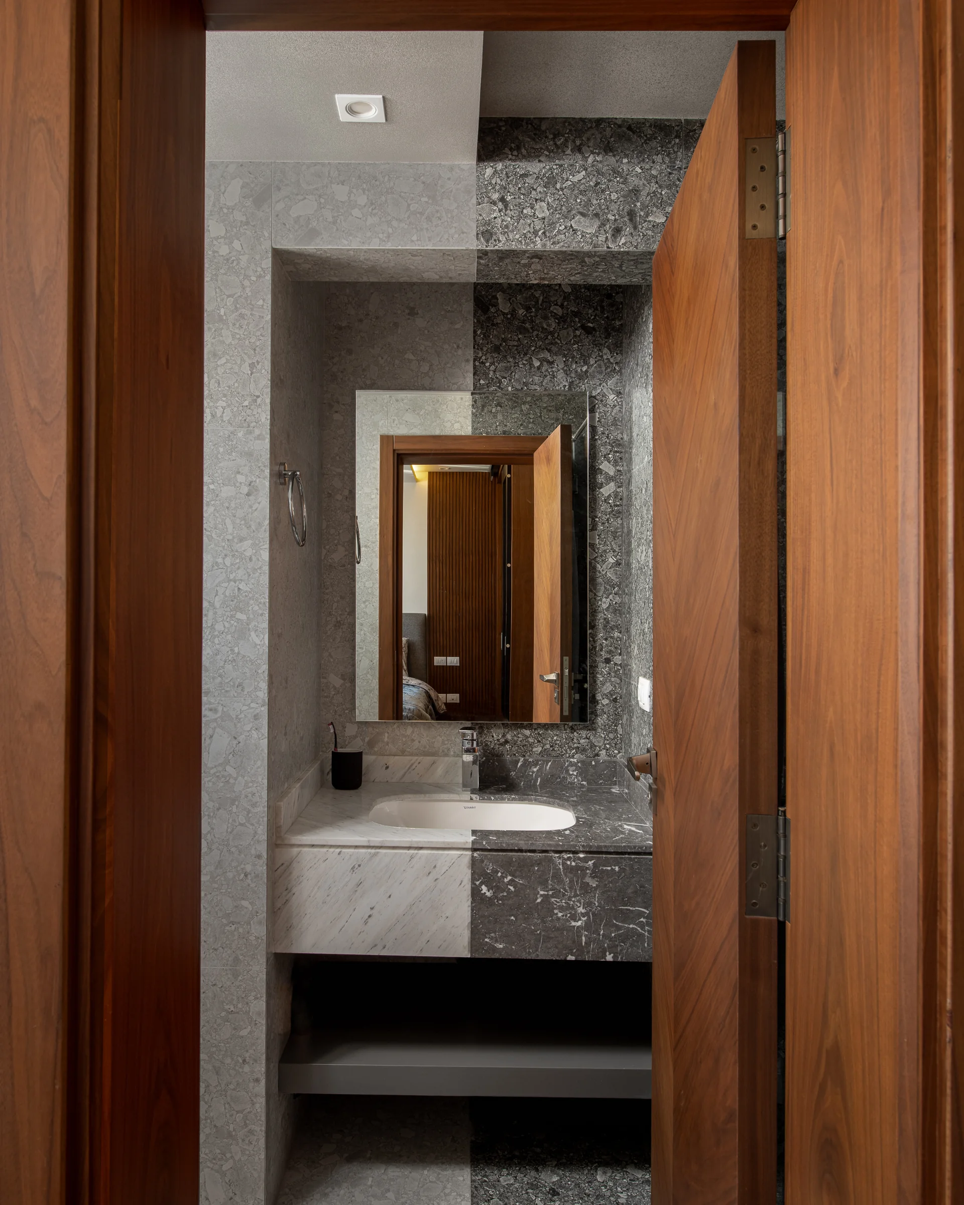 Guest bathroom glimpsed past a walnut door.
