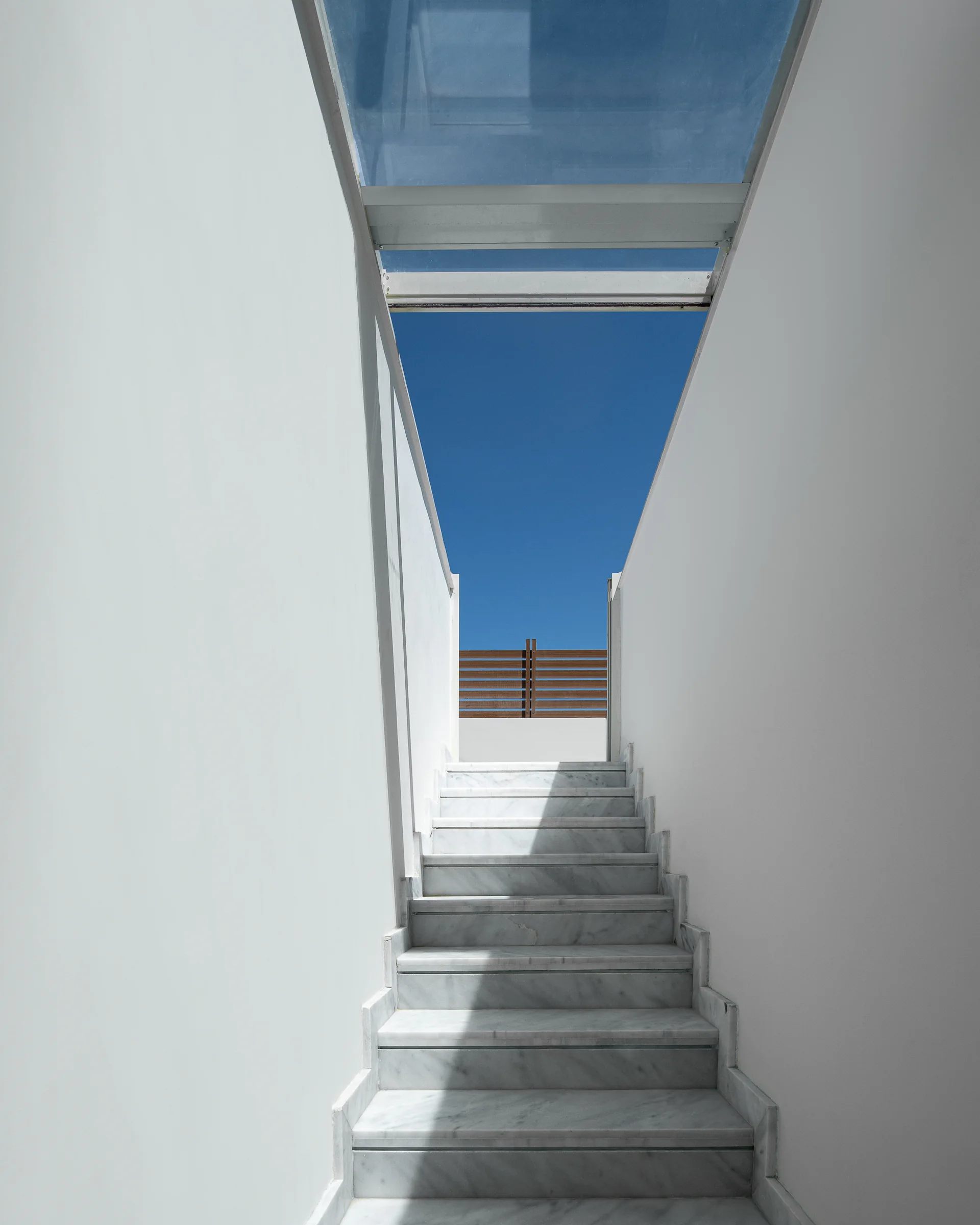 The stair between two white walls, open to the sky.