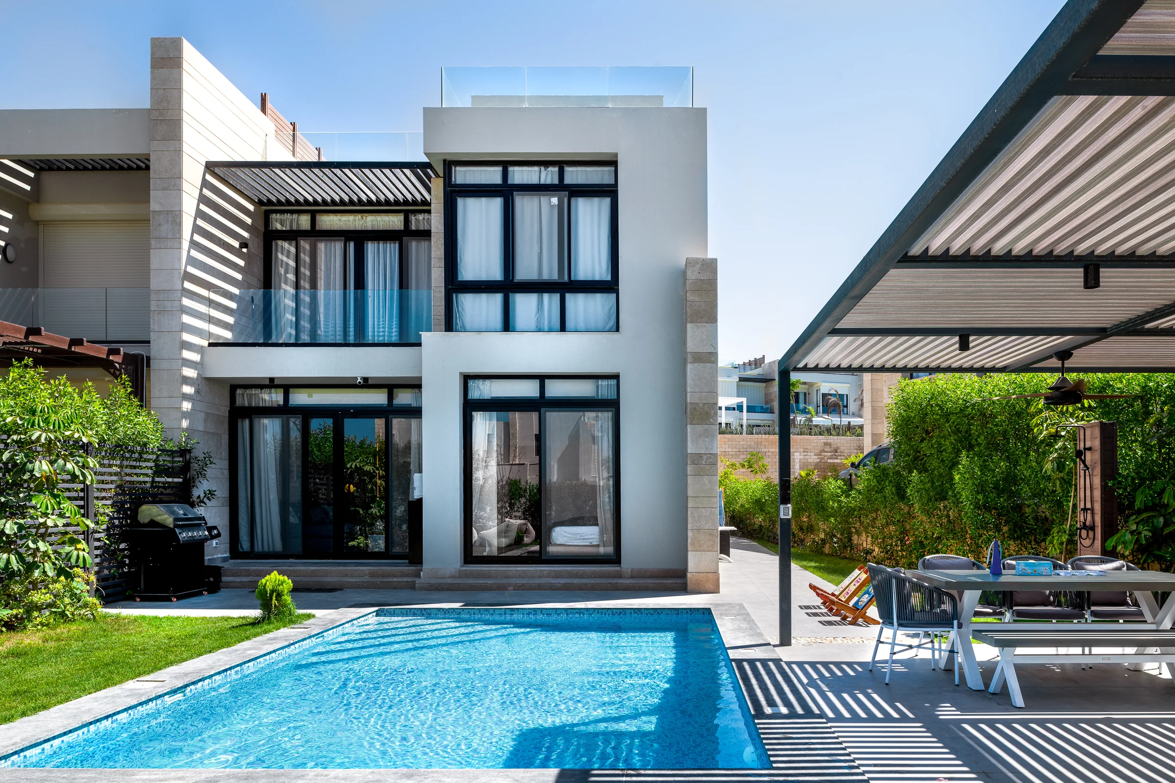 The house from the far side of the pool, glazing open to the terrace.