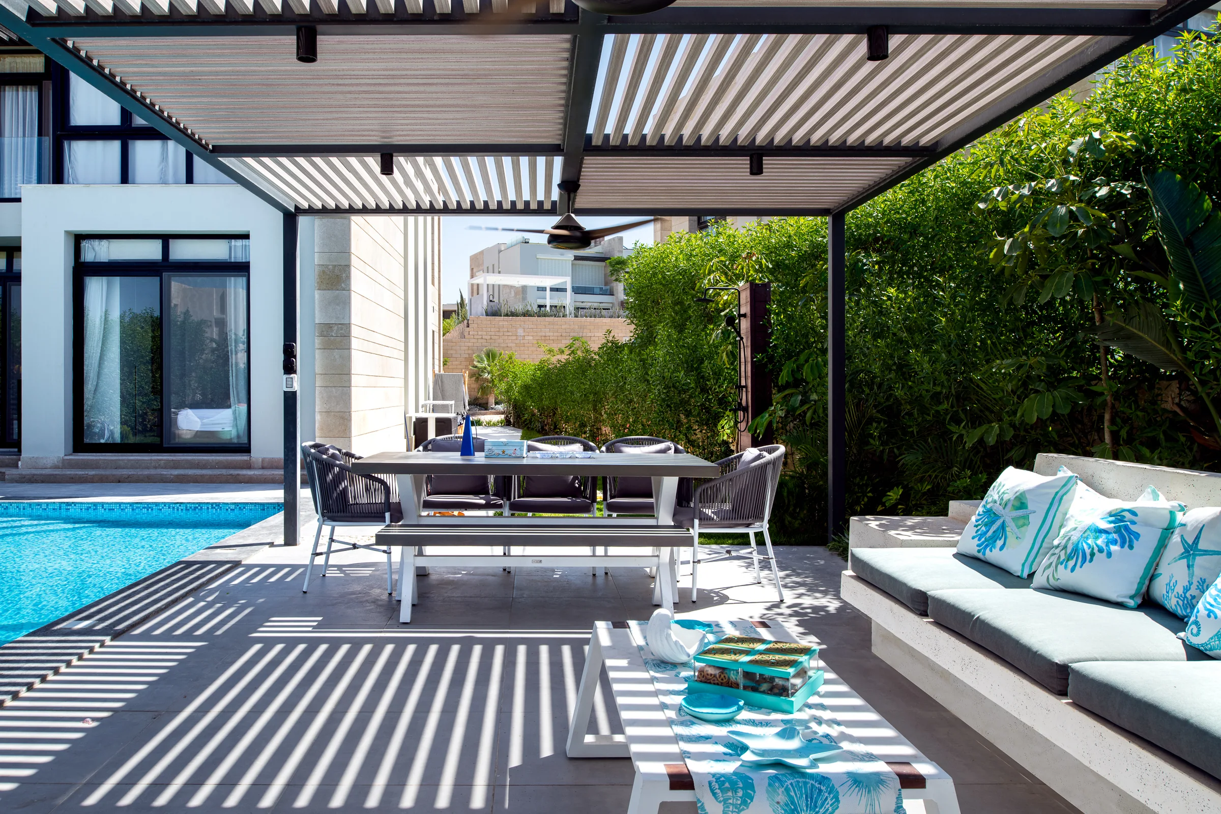 The long table set under the pergola beside the pool.