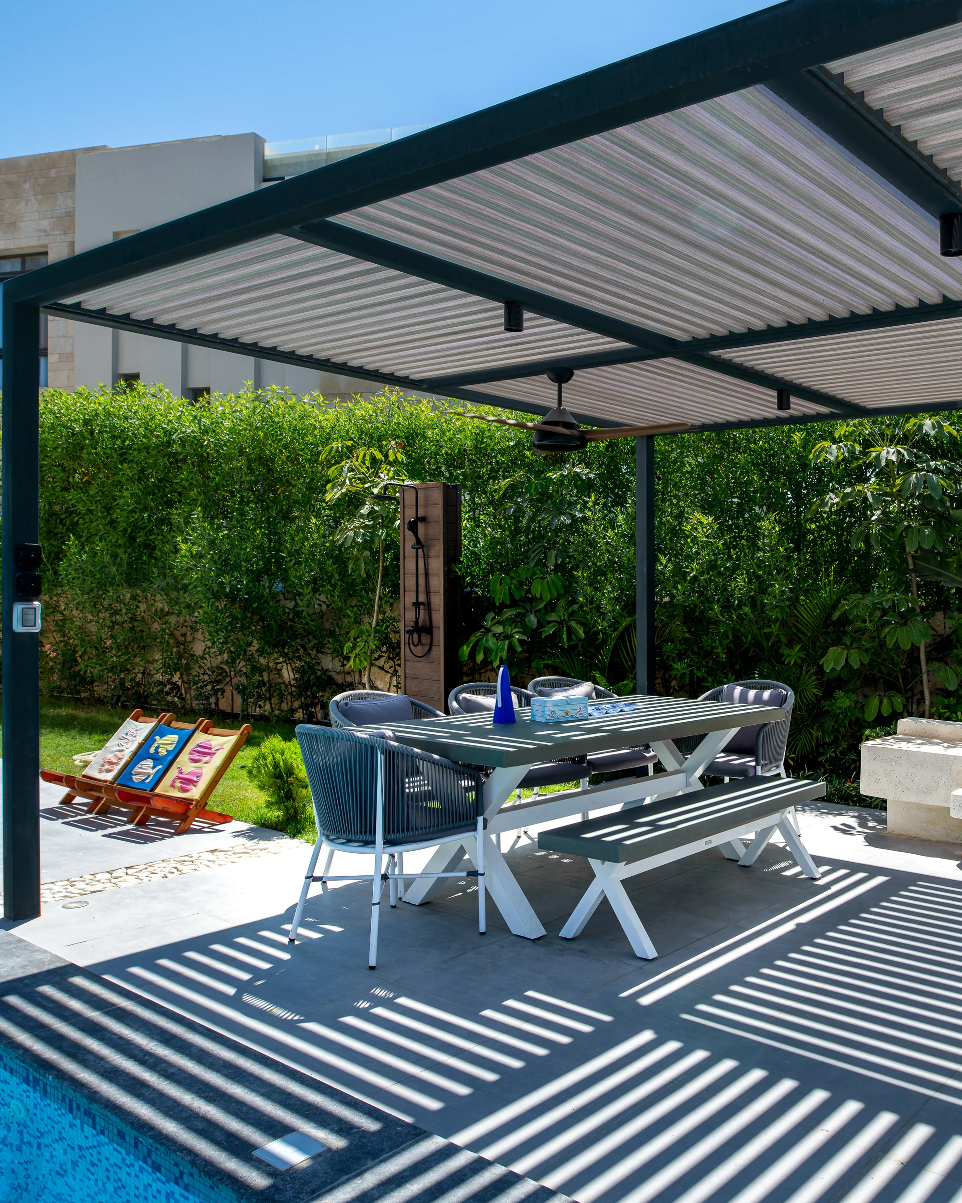 Dining under the pergola, shadow bars across the deck.