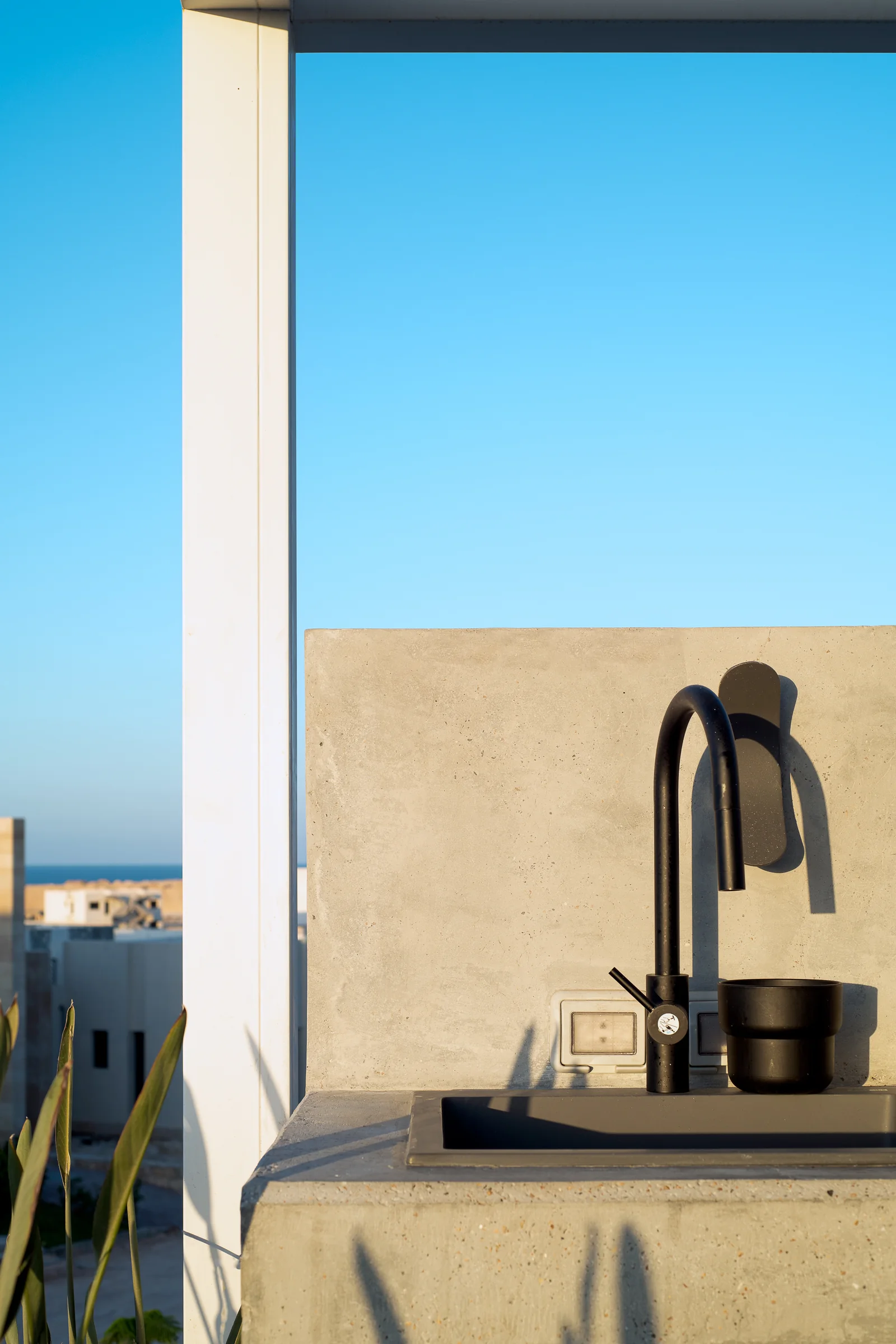 Outdoor shower against render, sea behind.