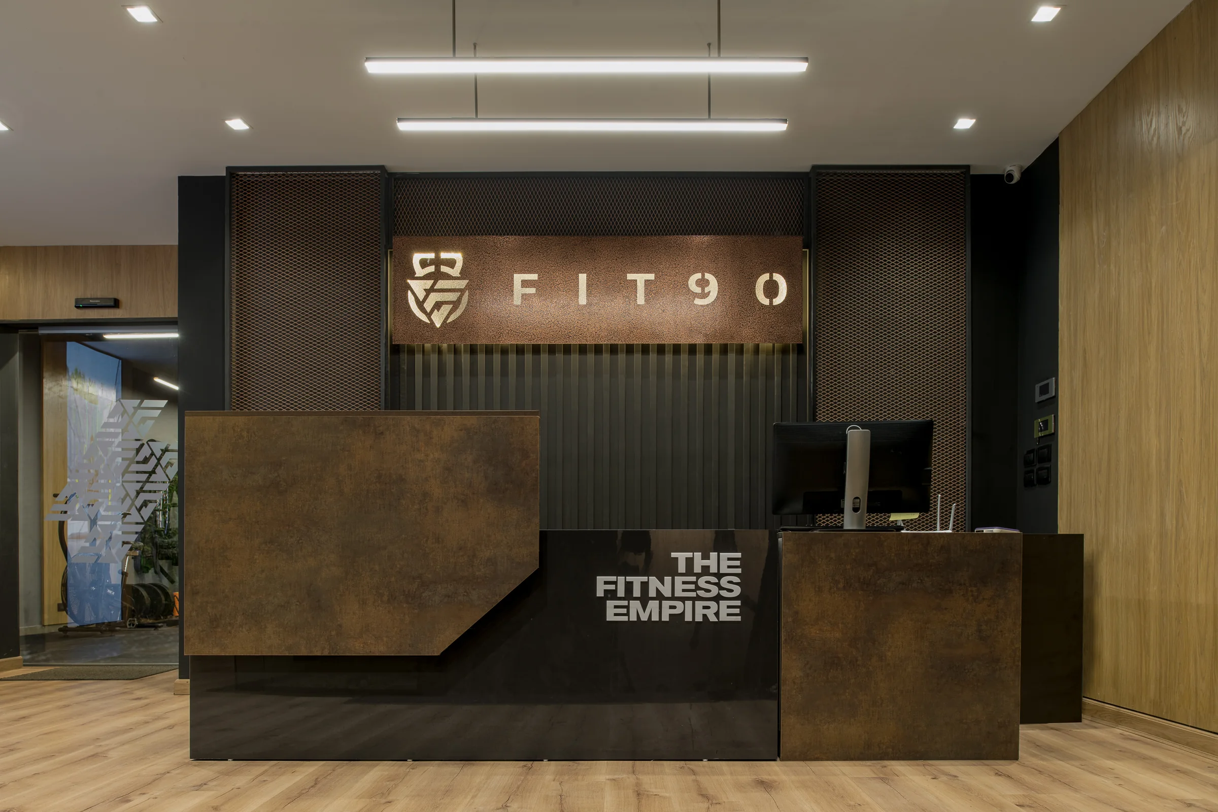 Reception desk in oxidised steel under an illuminated Fit 90 sign.