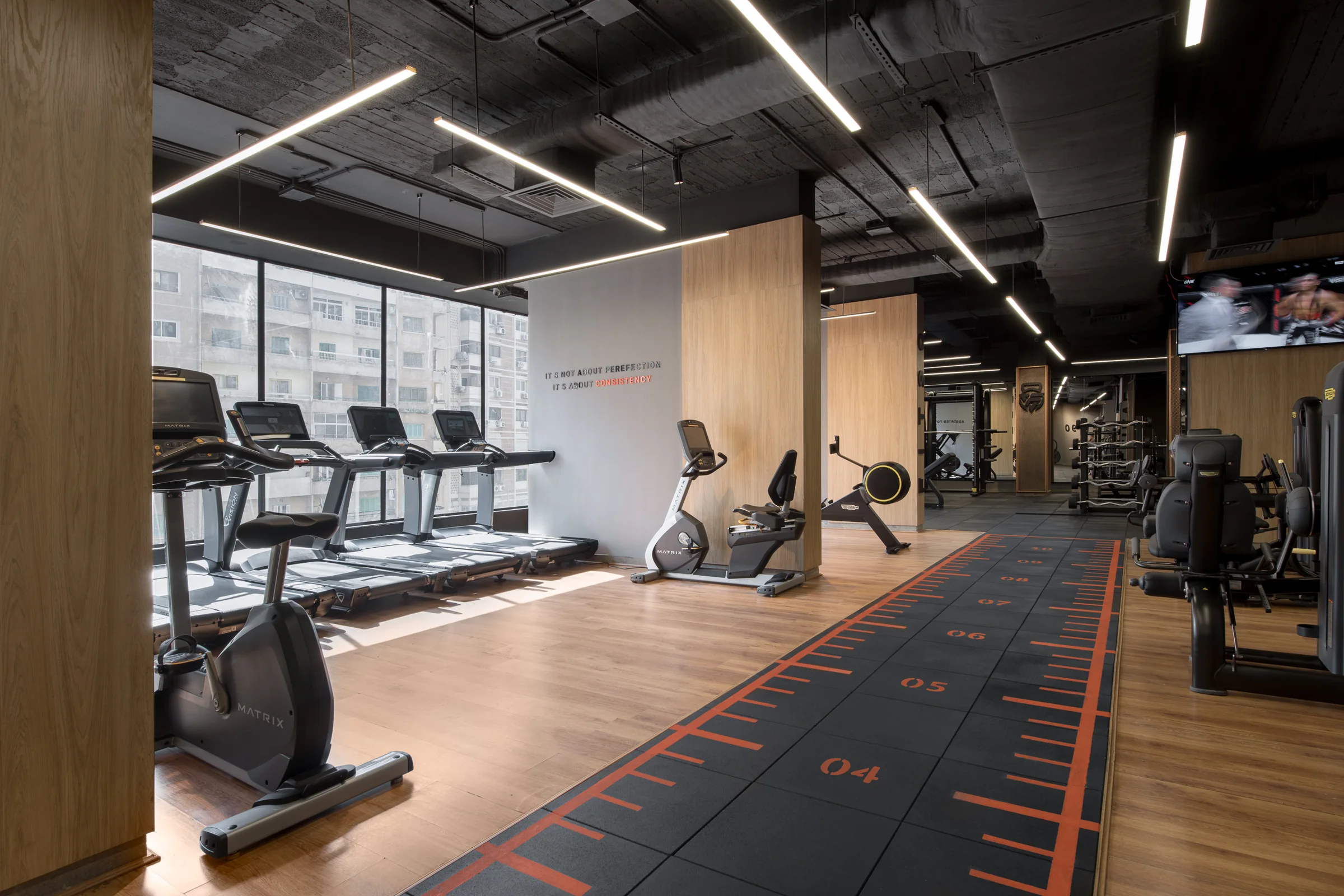 Cardio floor along the window wall, city light across the machines.