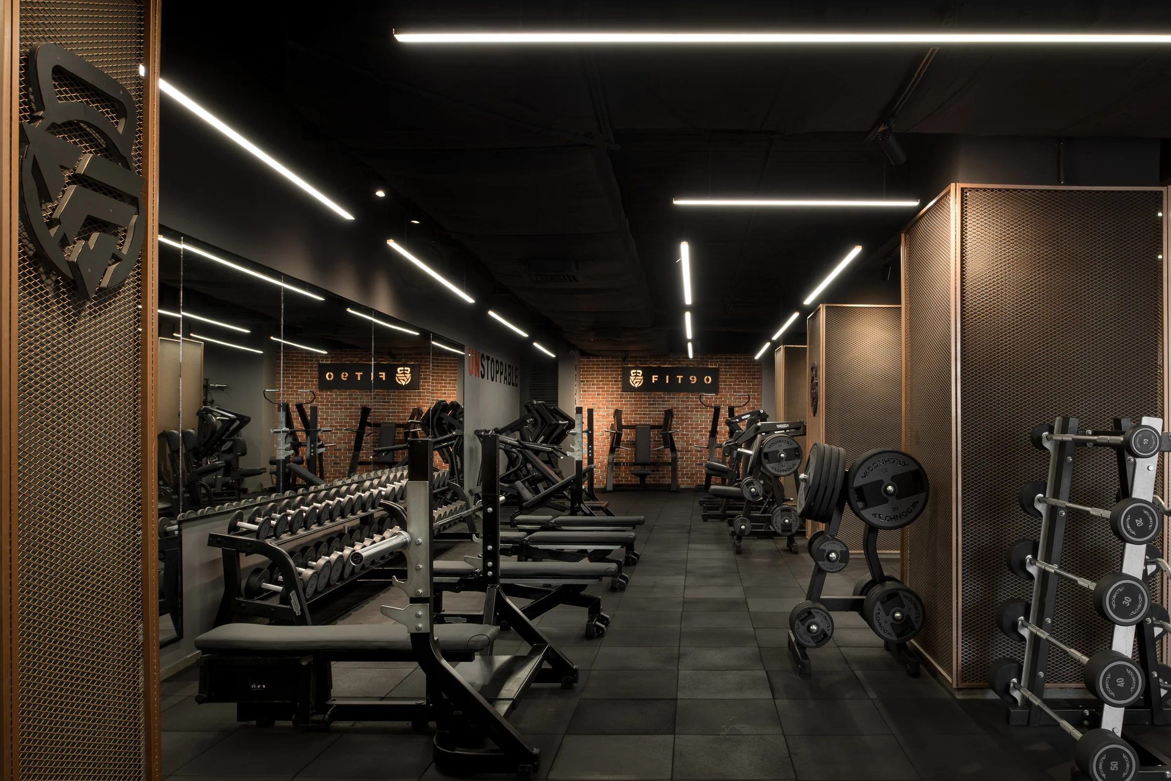 Free-weights floor: racks, benches and dark rubber flooring.