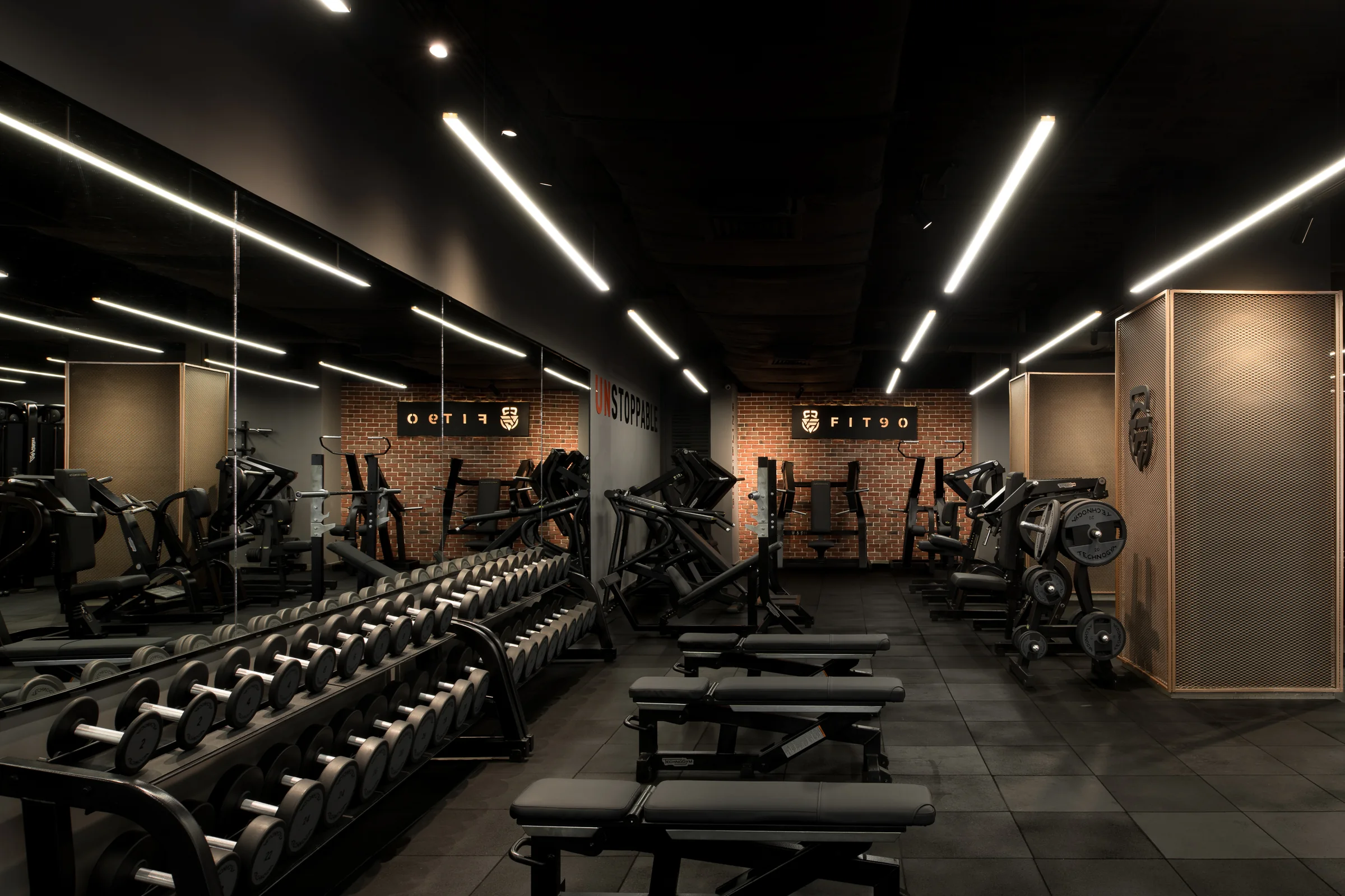 The weights room wide, mirrored end wall doubling the space.
