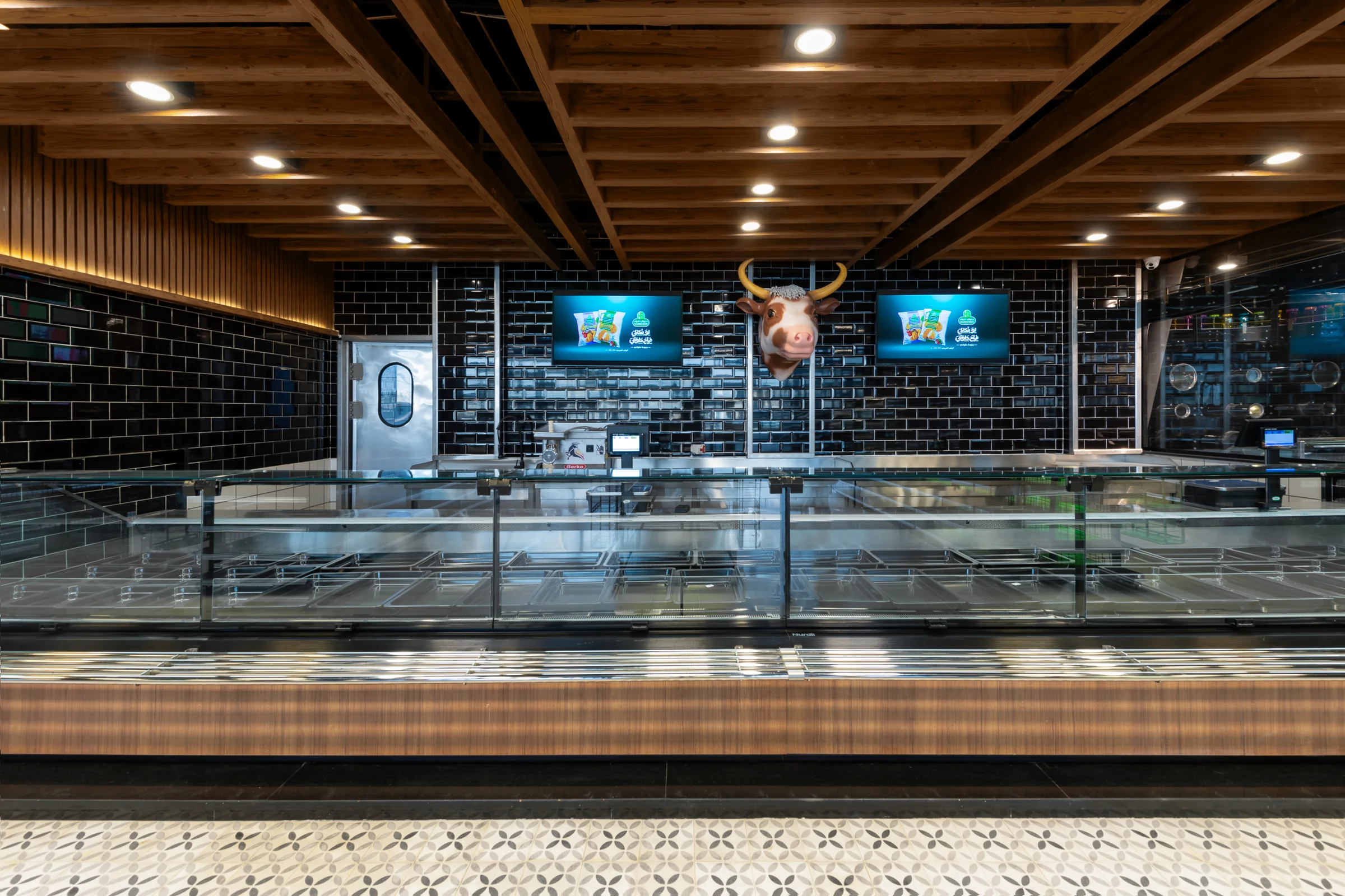 Butchery counter under the cattle sign, tiled wall behind.