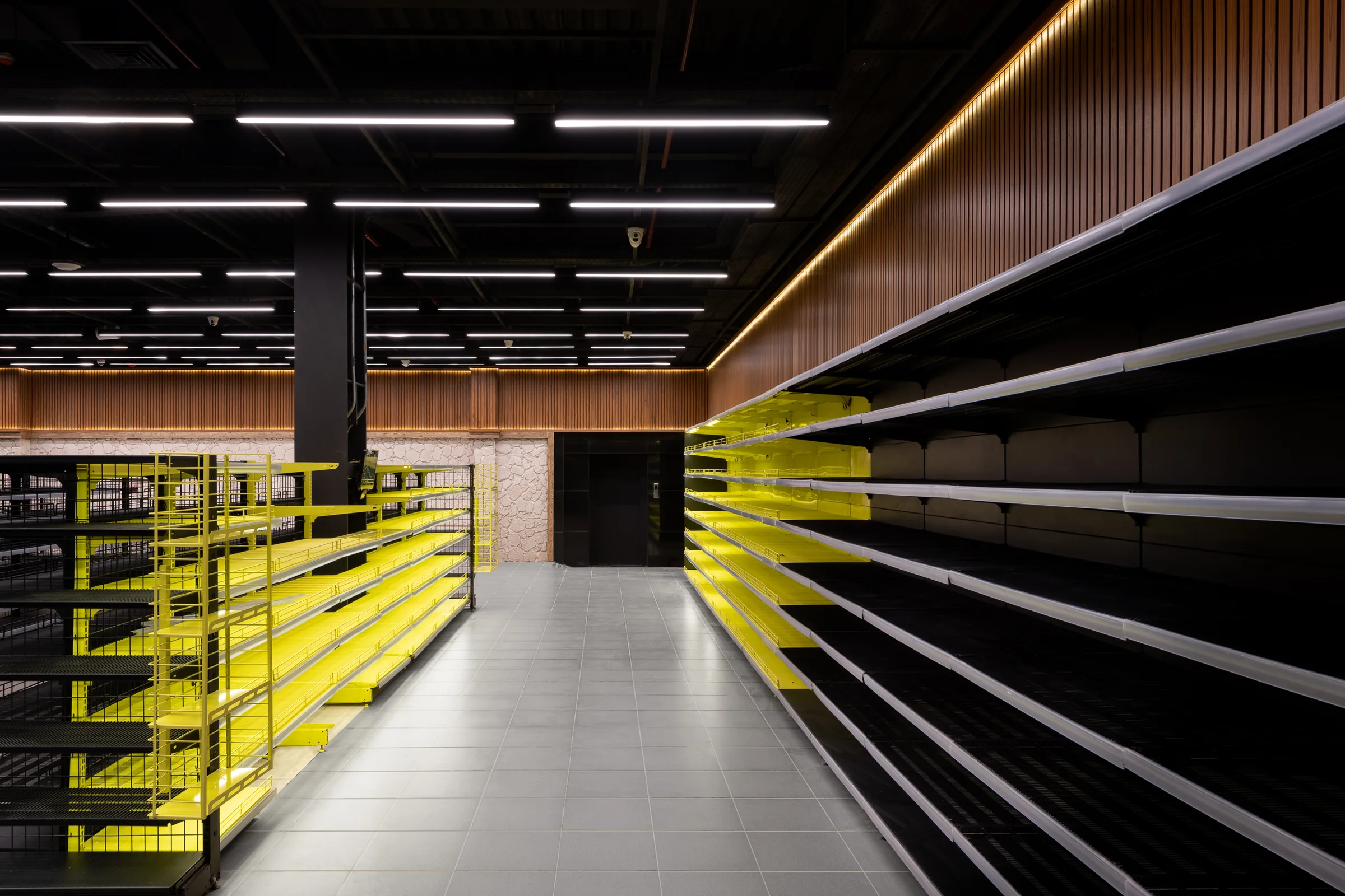 Empty shelving in yellow steel, receding into the dark.