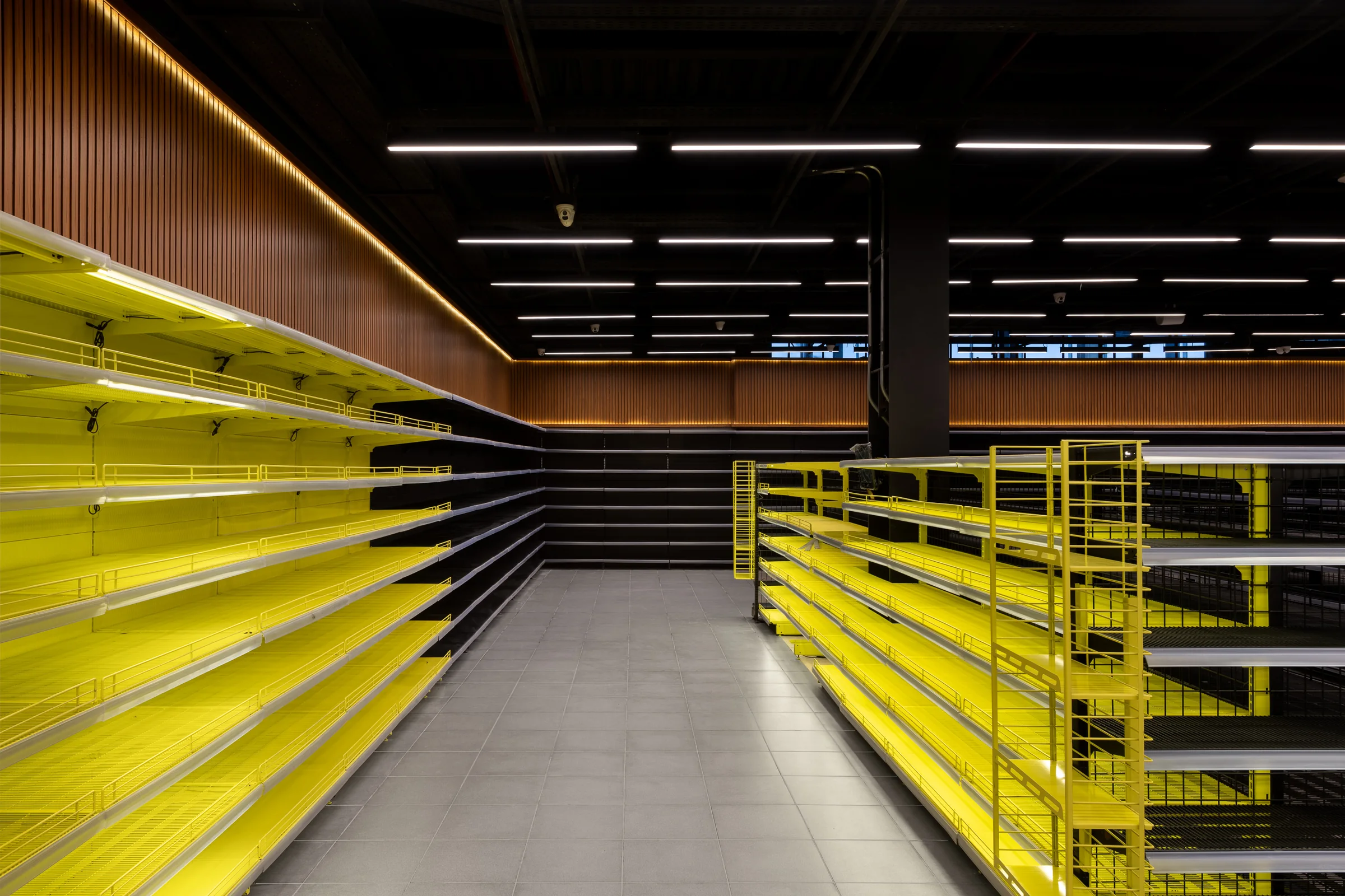 Yellow racking from the aisle end, ceiling services exposed.