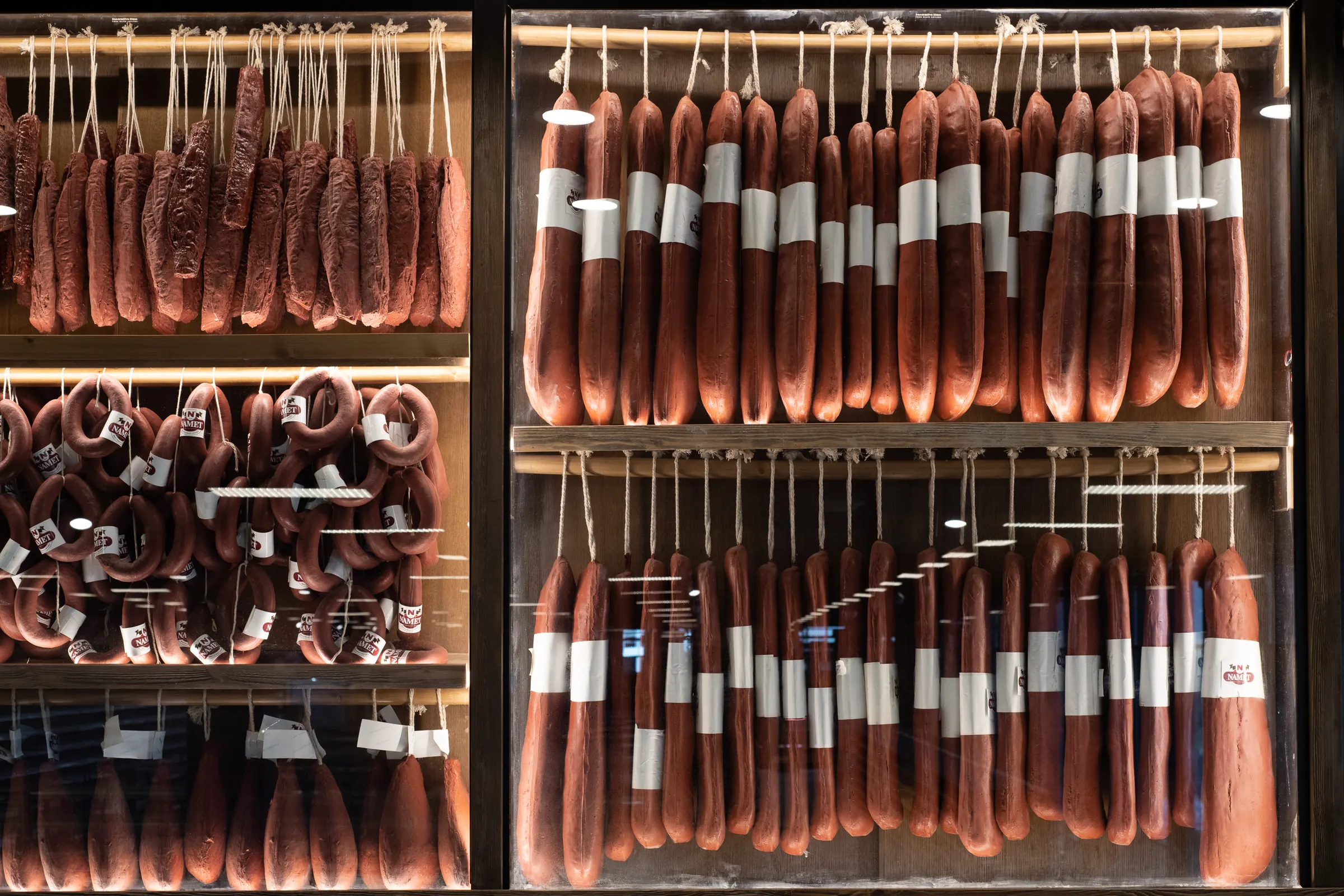 Cured meats hung in rows against black tile.