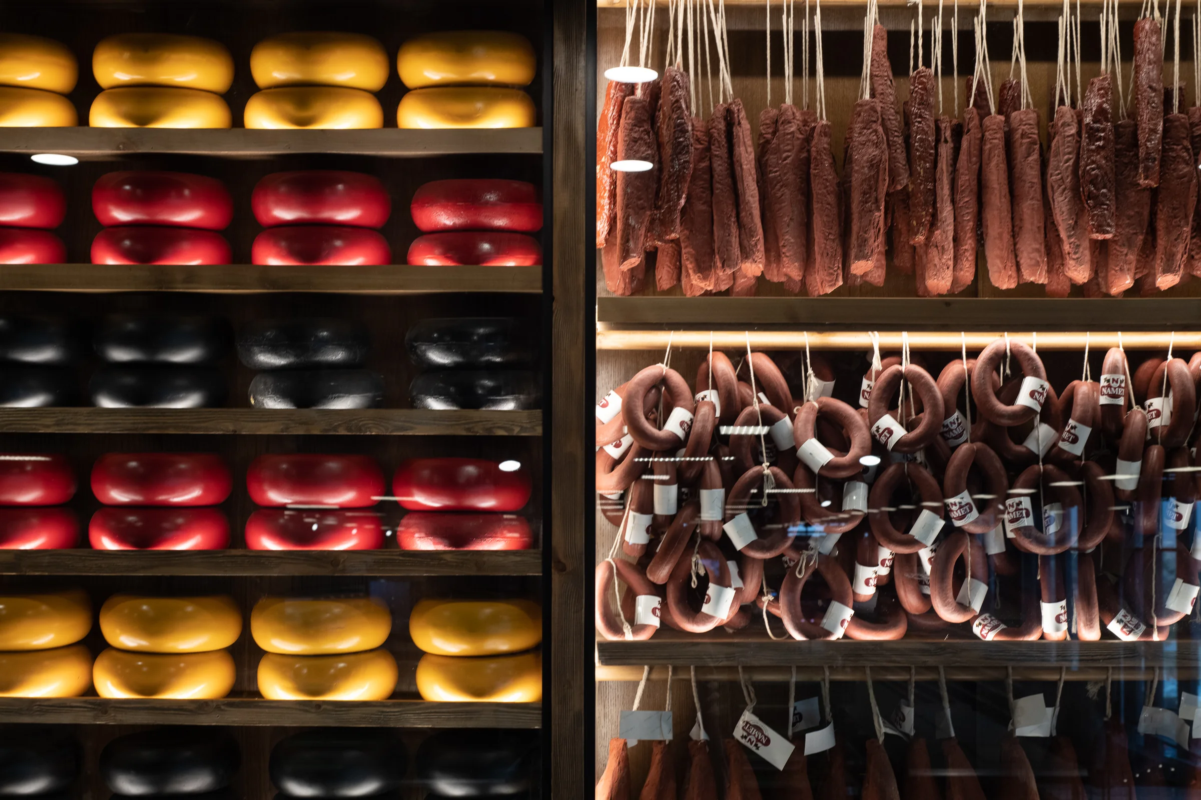 Cheese and charcuterie stacked on the wall shelving.
