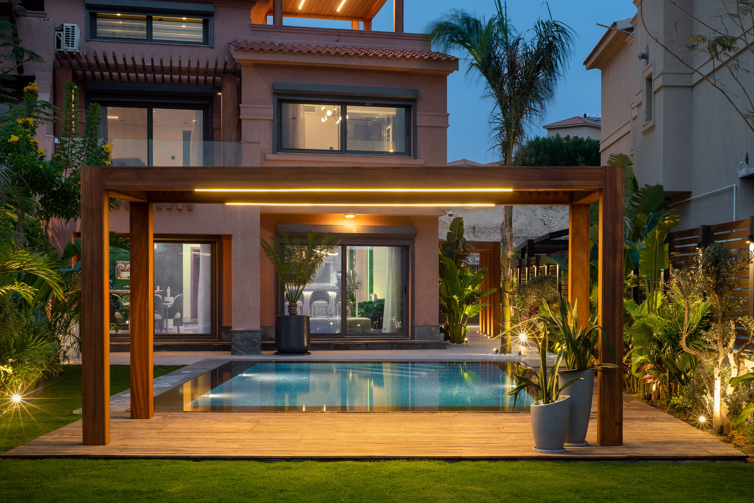 The same deck after dark, the pool lit from within.