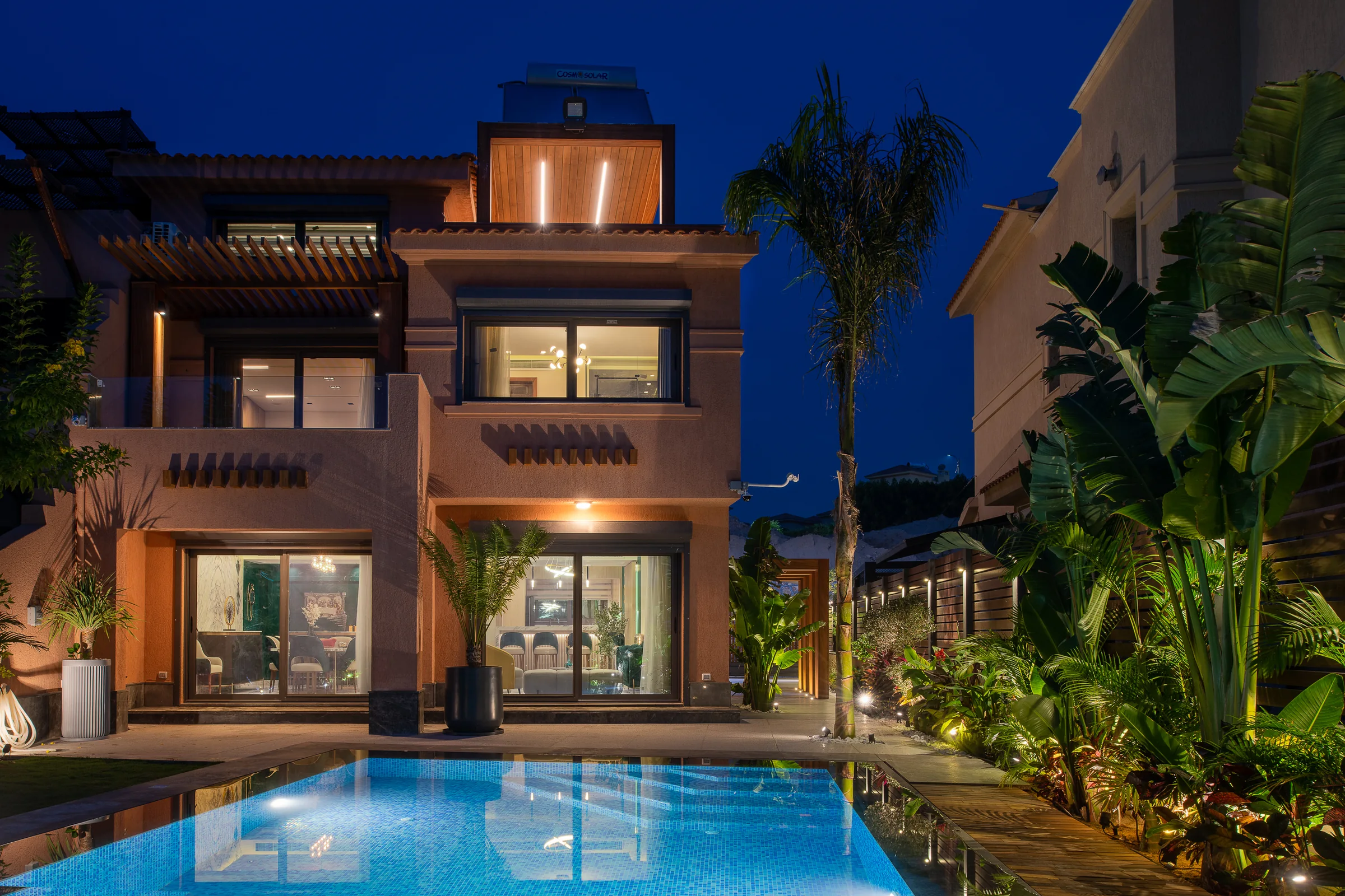 The villa at night from across the pool, every floor lit.