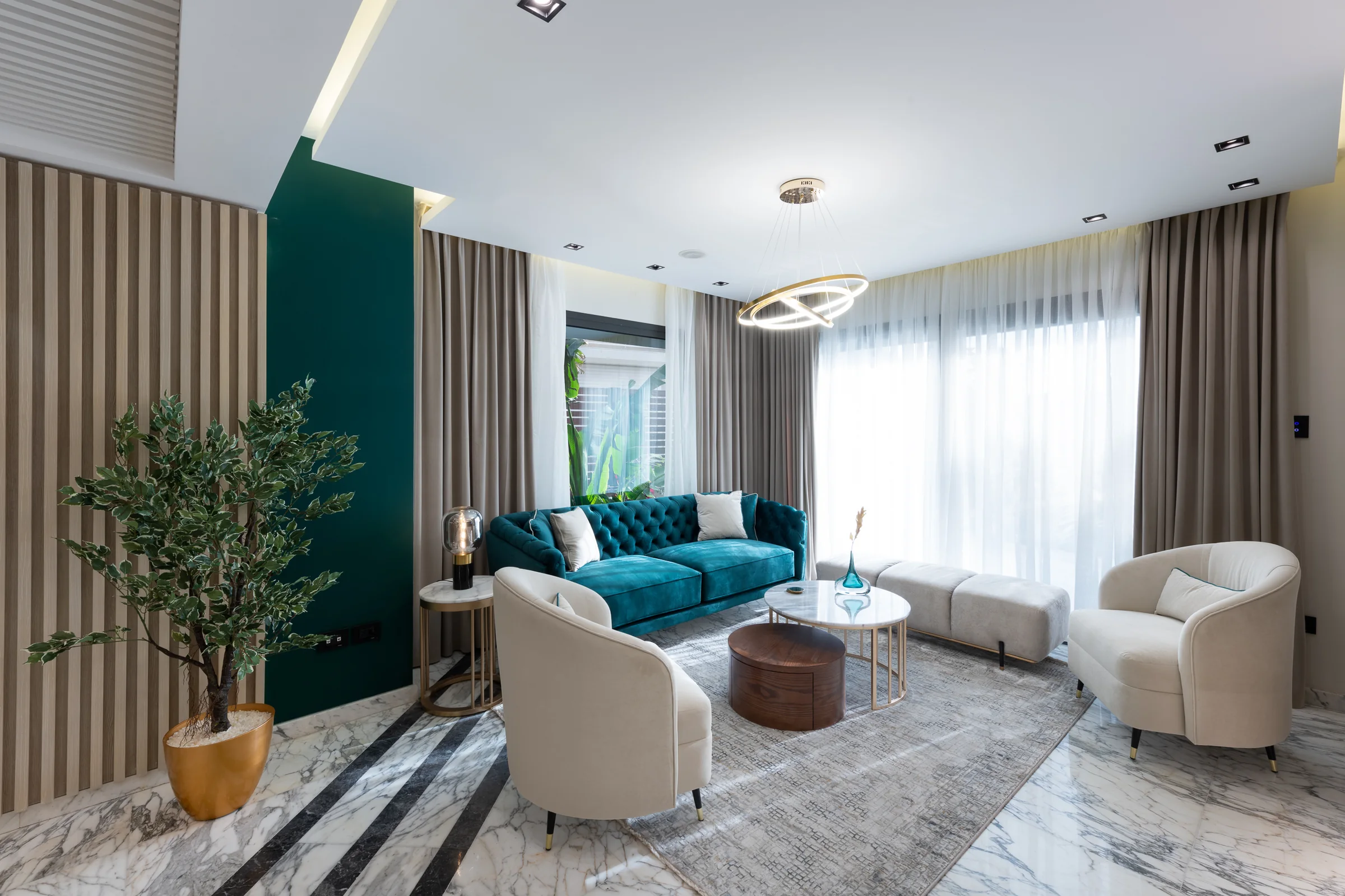 Living room with a teal velvet sofa and marble floor.
