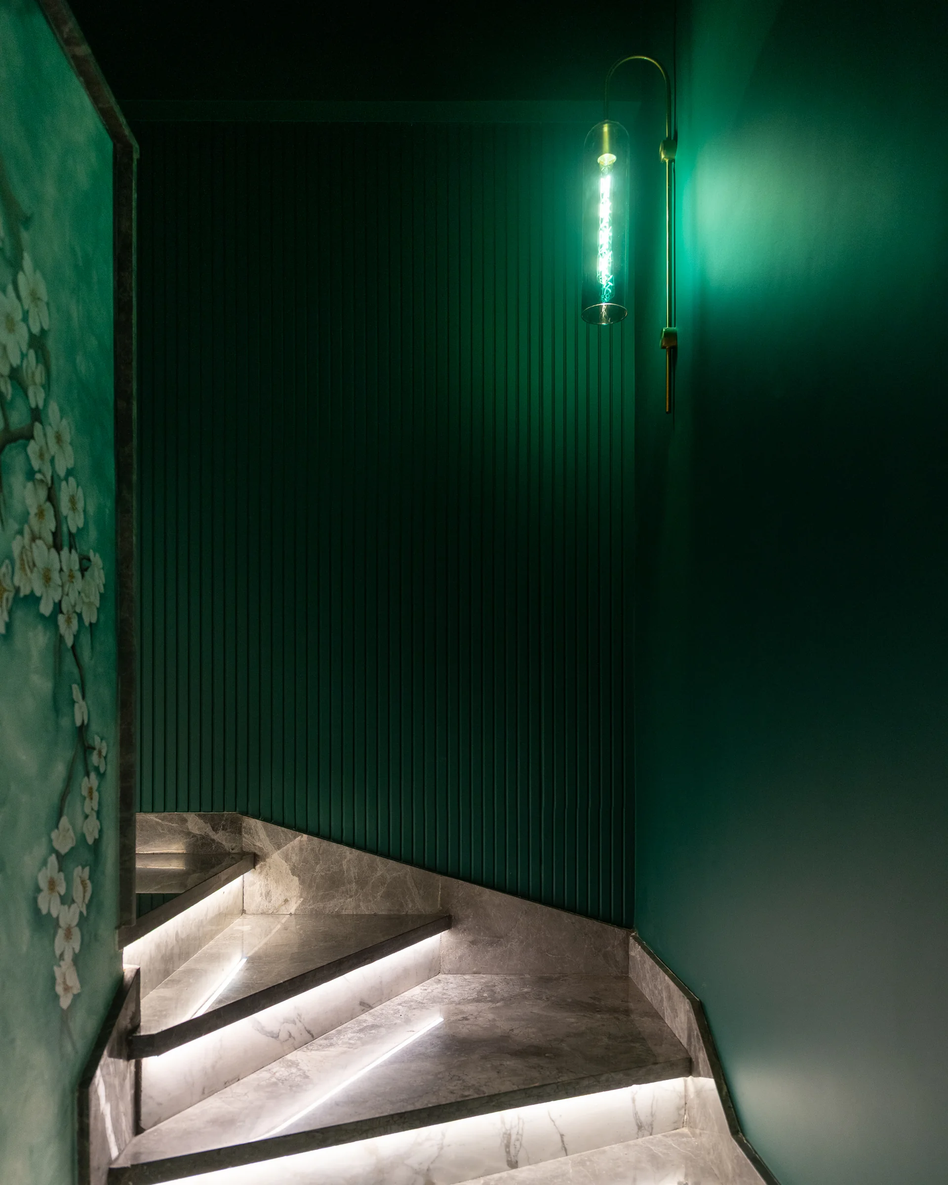 Stair wall in emerald, lit from the reveal.