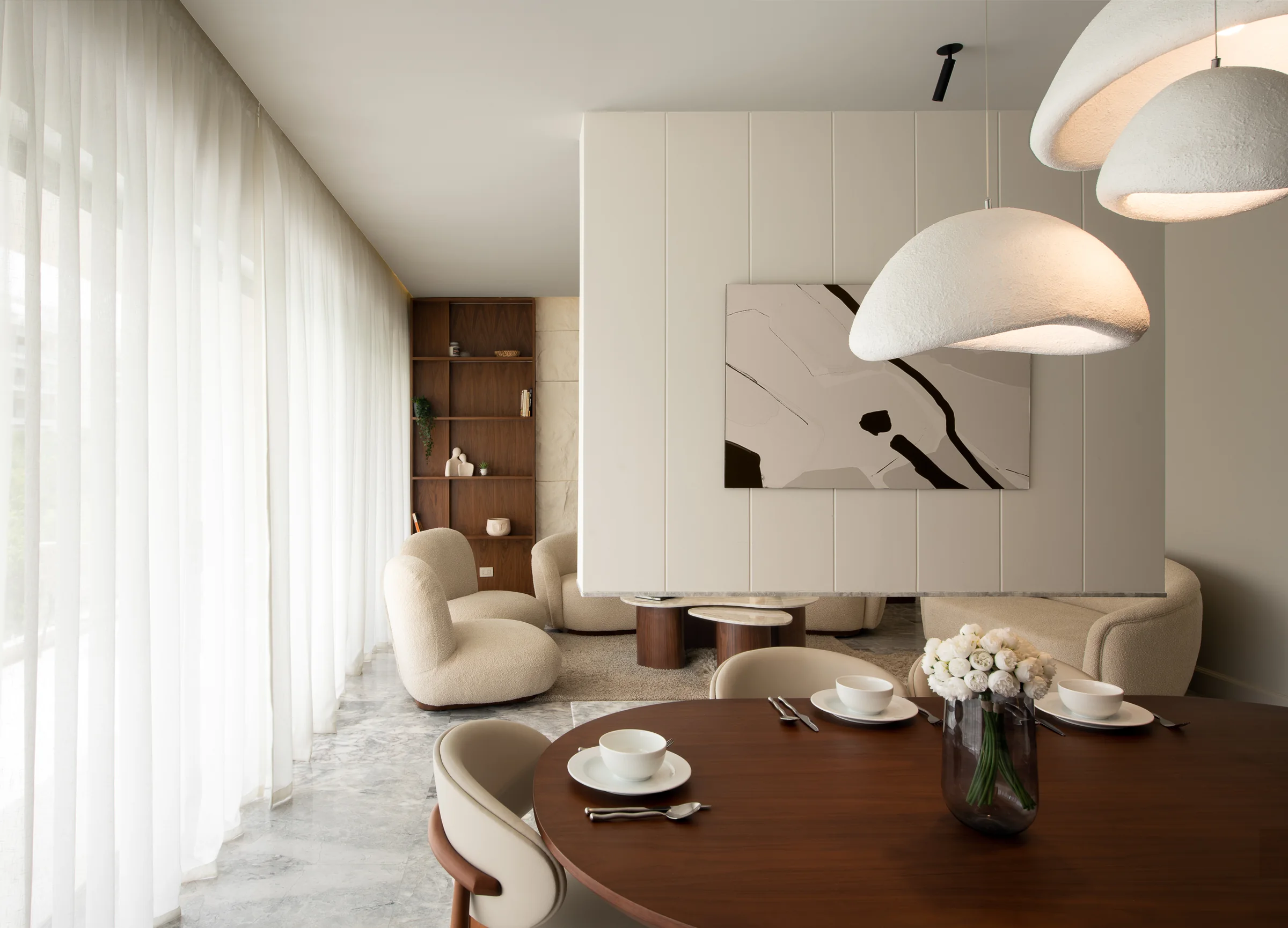 Dining and living rooms under dome pendants, artwork on the panelled wall.