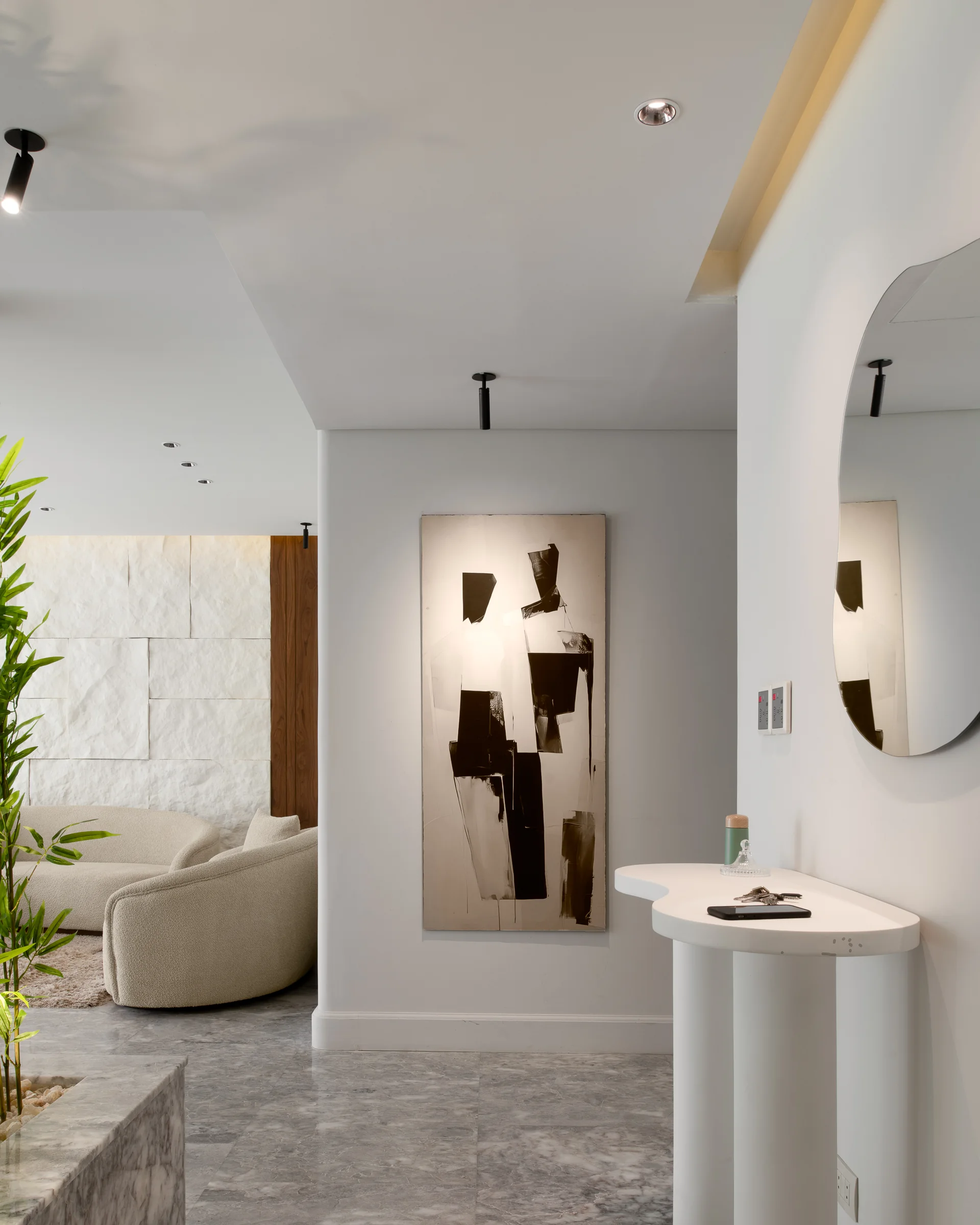 Entrance console with a sculptural mirror and a stone-clad wall beyond.
