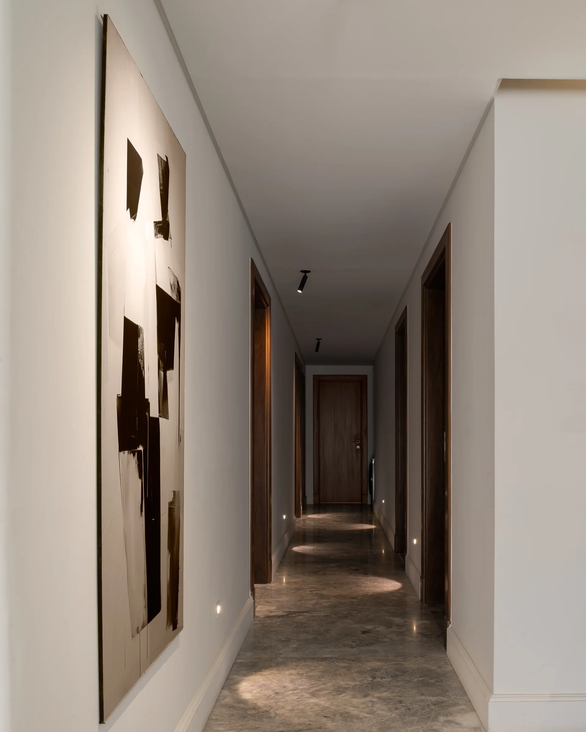 Corridor hung with a run of framed works, doors receding.