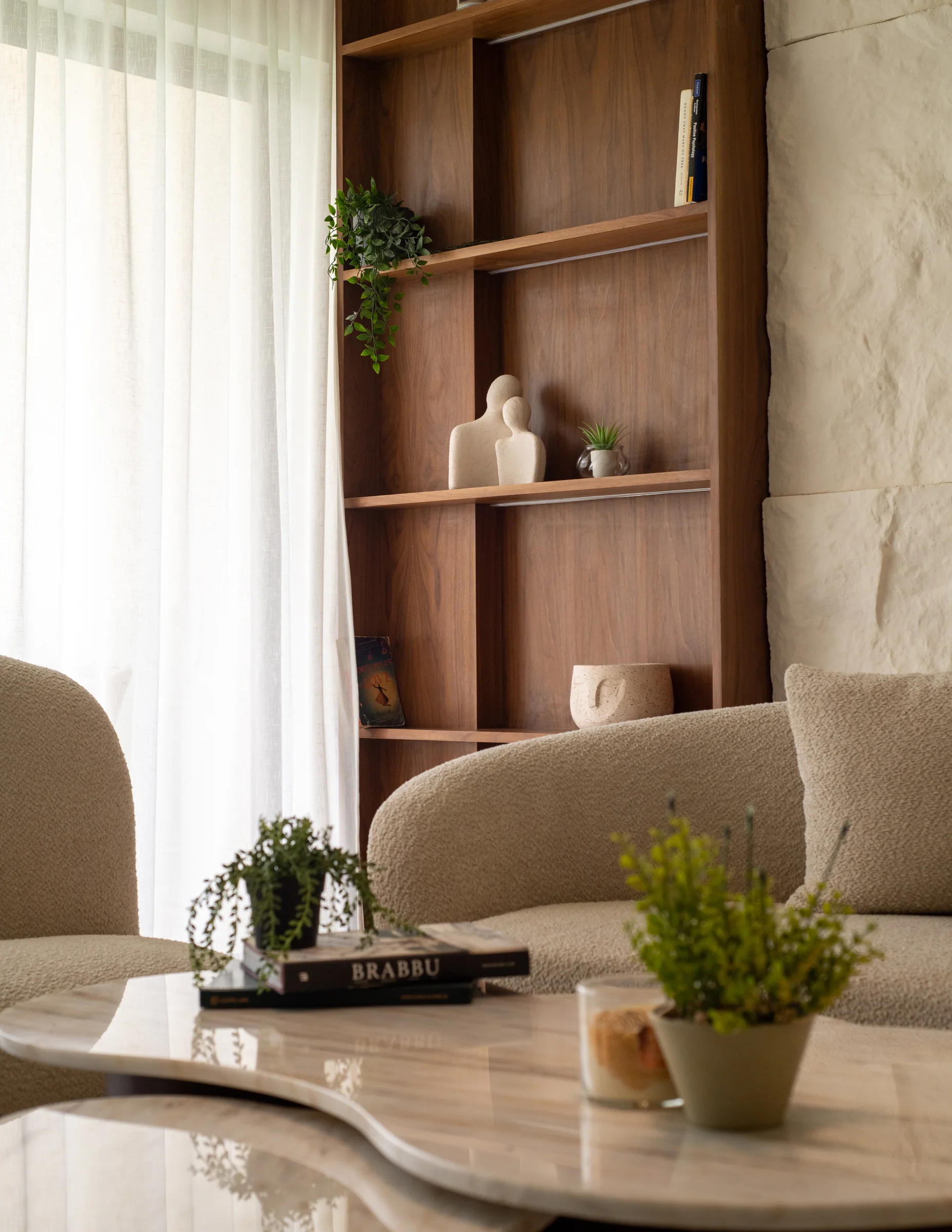 Walnut shelving with ceramics and a plant on the marble table.