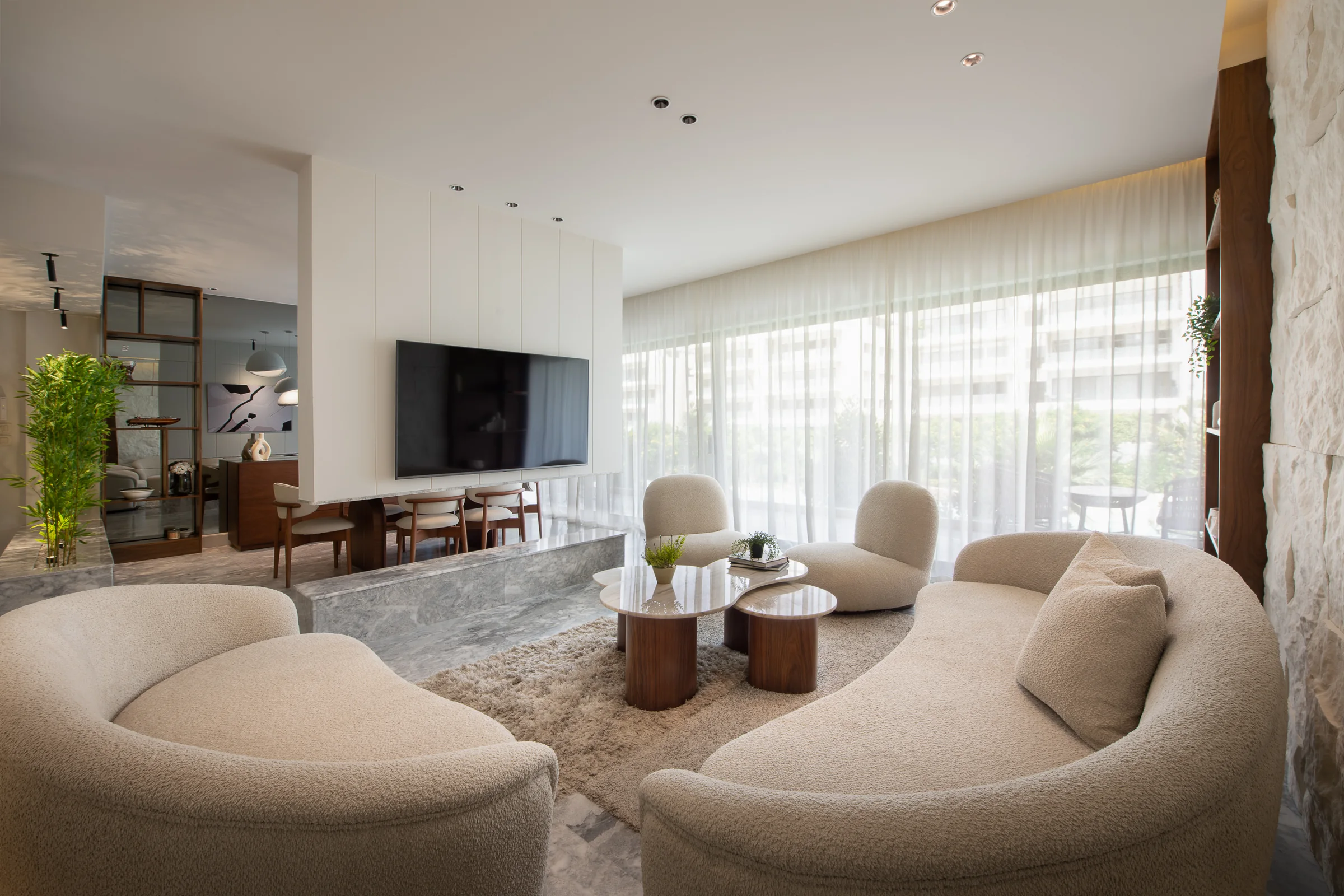 Living room with the dining room beyond, greenery at the window.