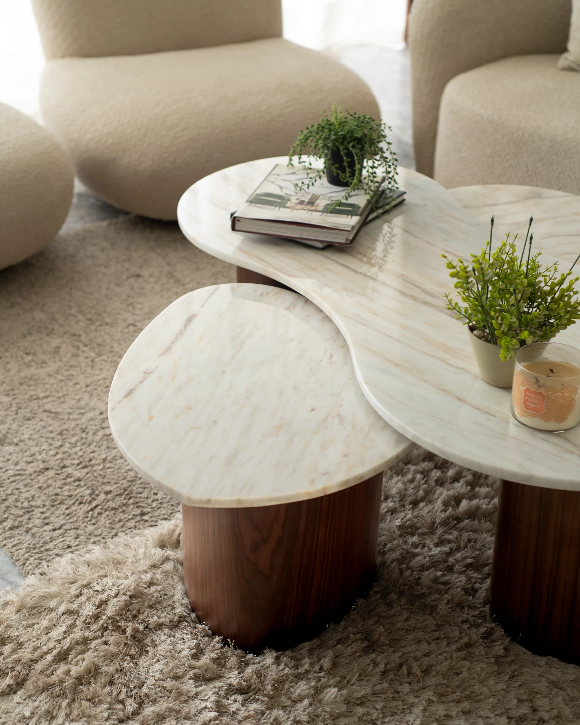 Close detail: two marble coffee tables on a deep pile rug.