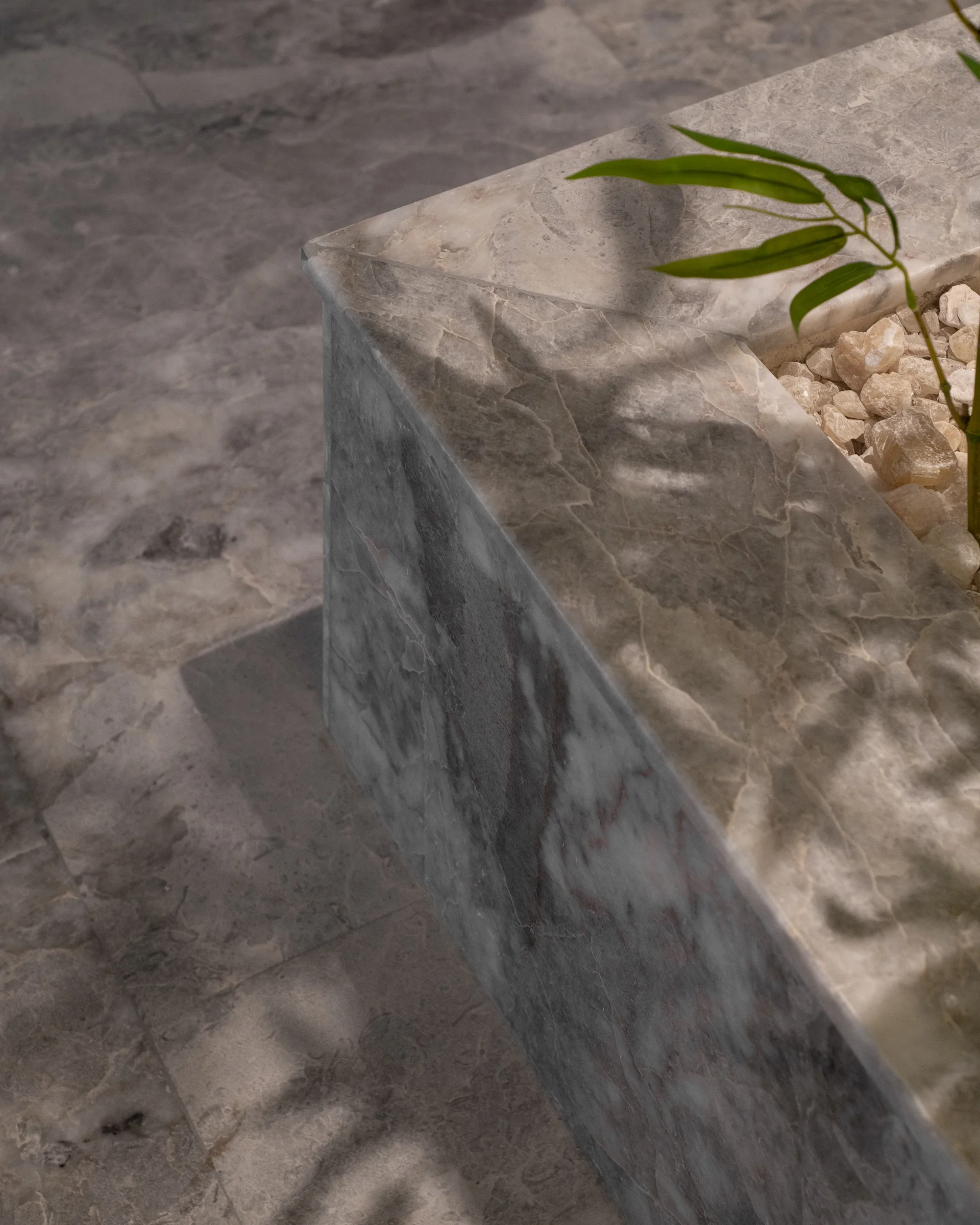 Marble counter edge with a bamboo shoot and pebbles.