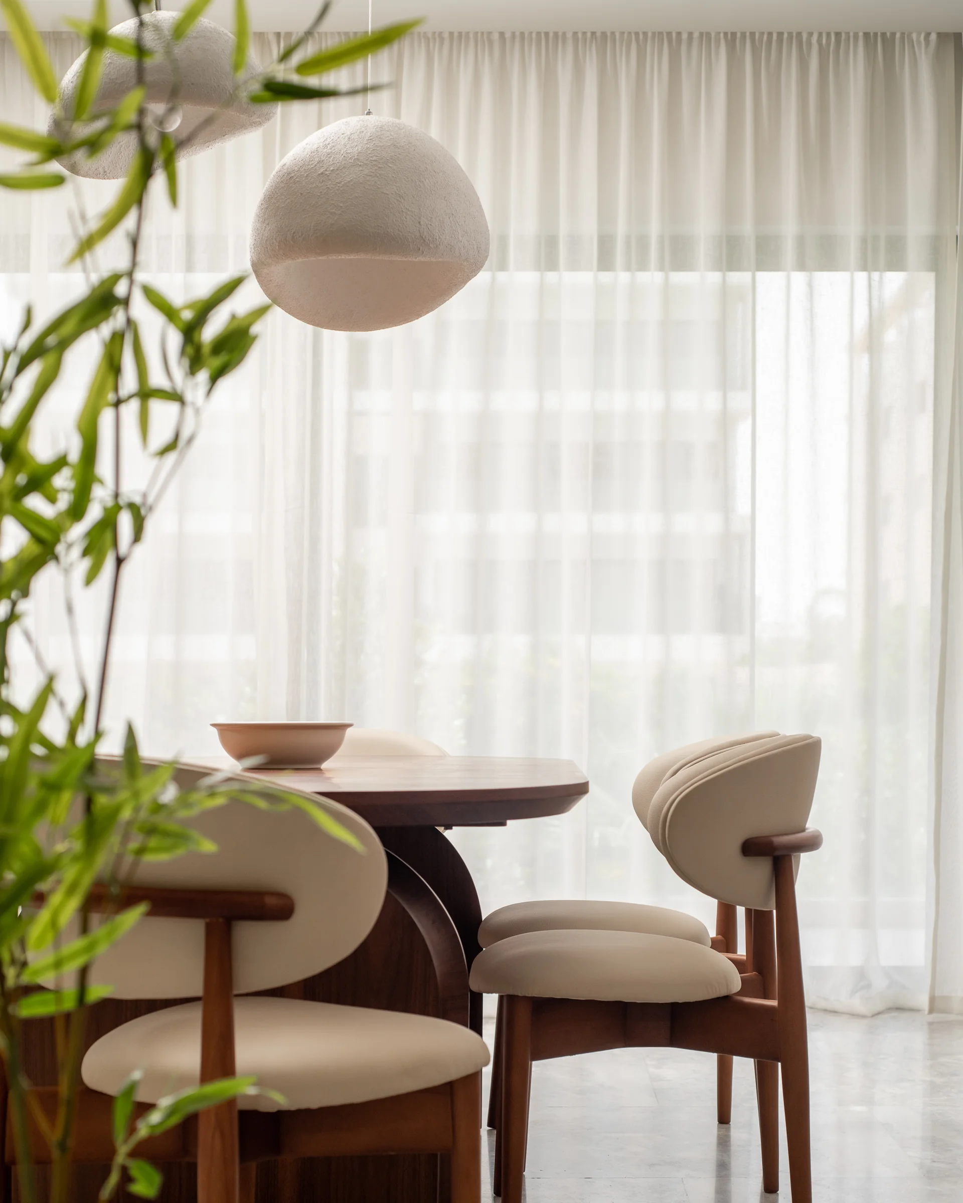 Curved dining chairs and a bowl, backlit by the window.