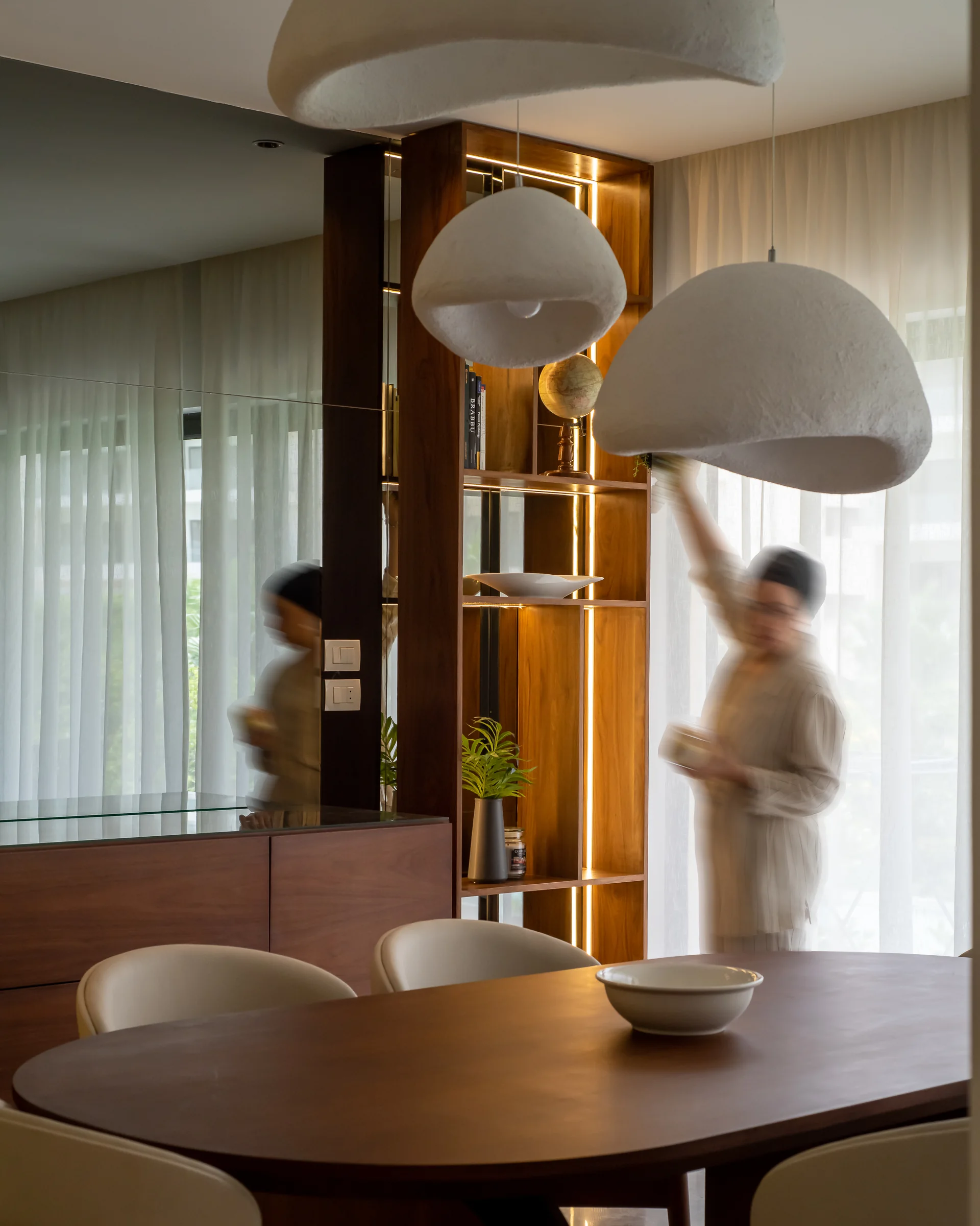 Dining table and figures reflected in the mirrored joinery.