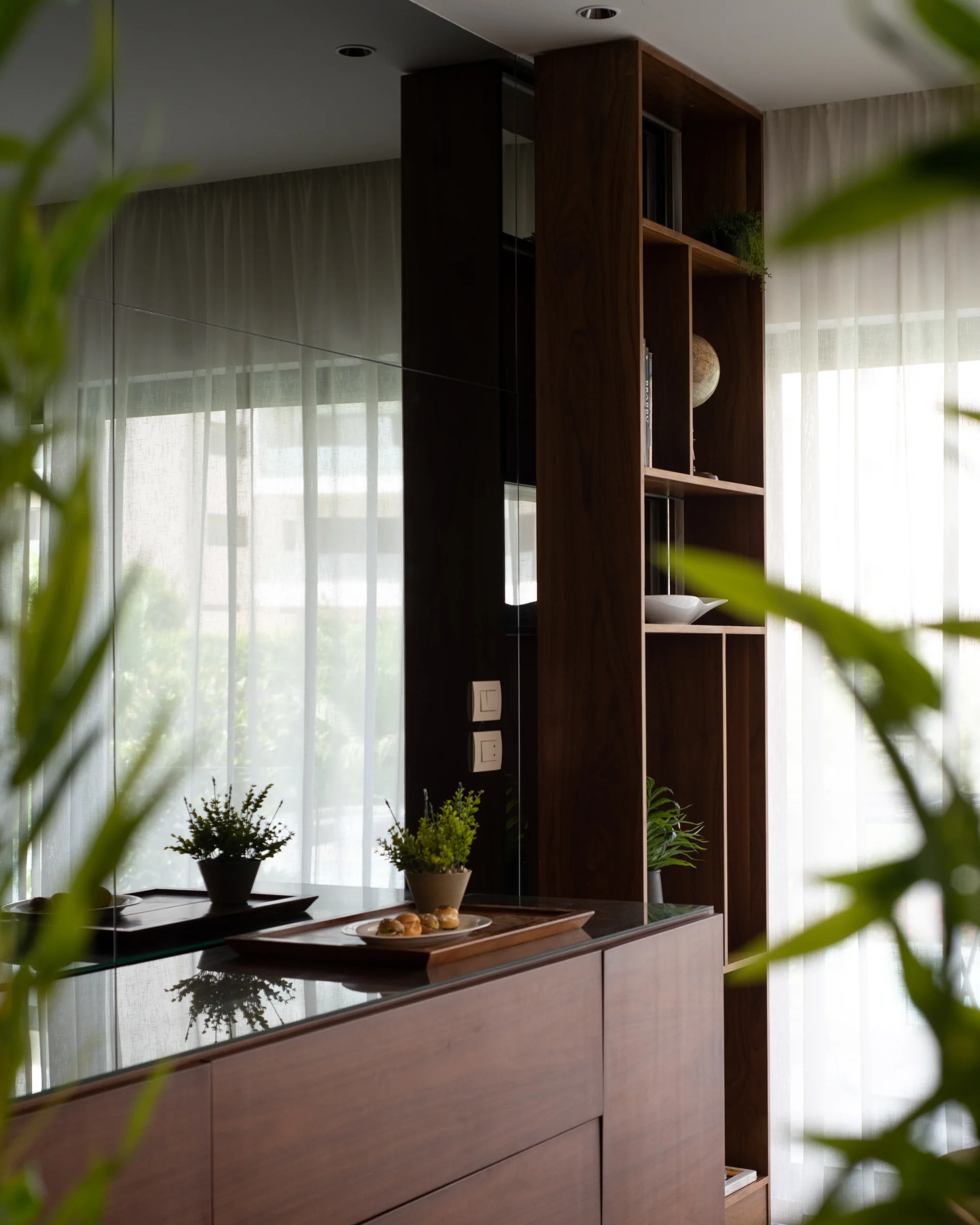 Walnut credenza and shelving with ceramics and plants.