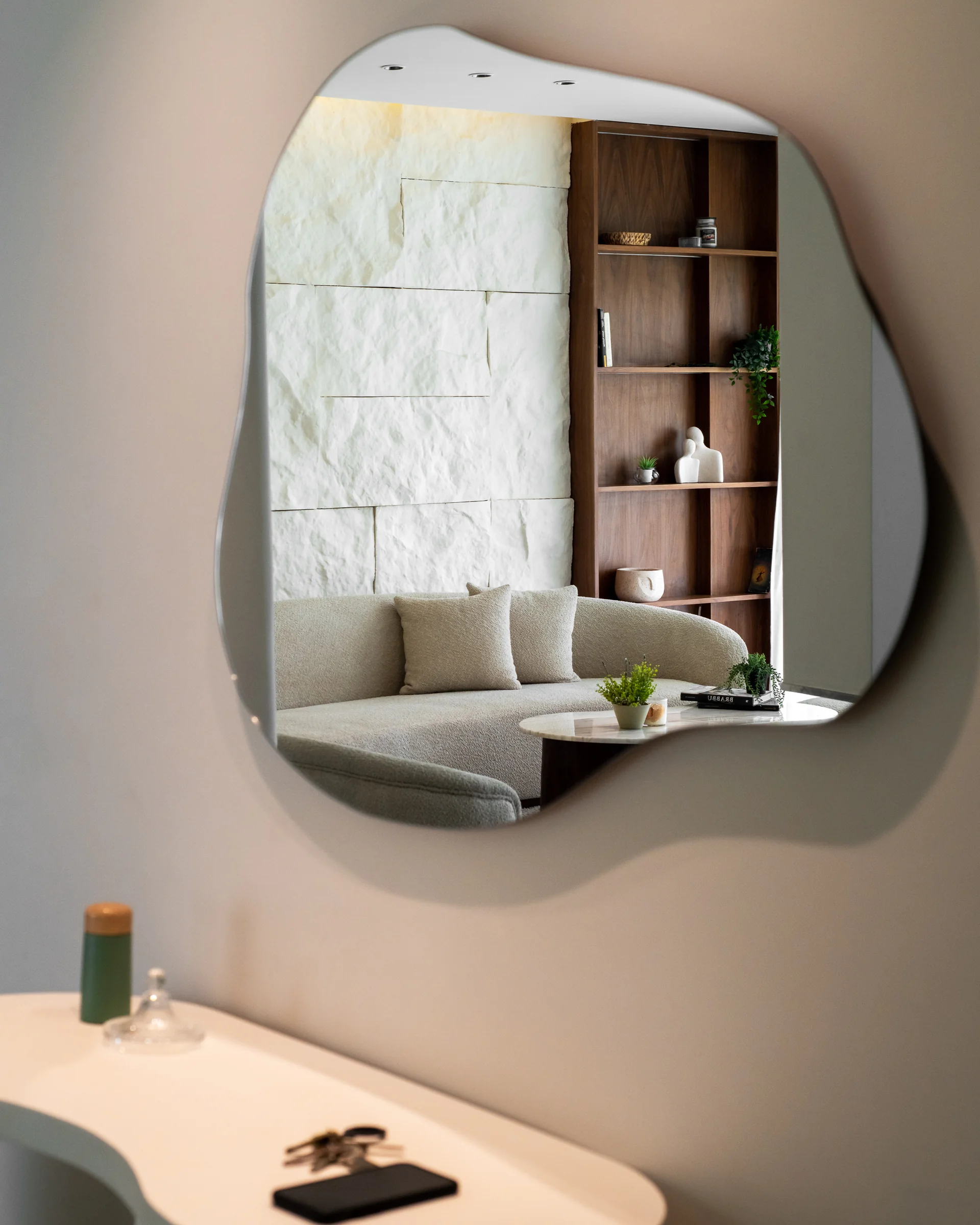 Organic mirror above the console, the living room reflected.