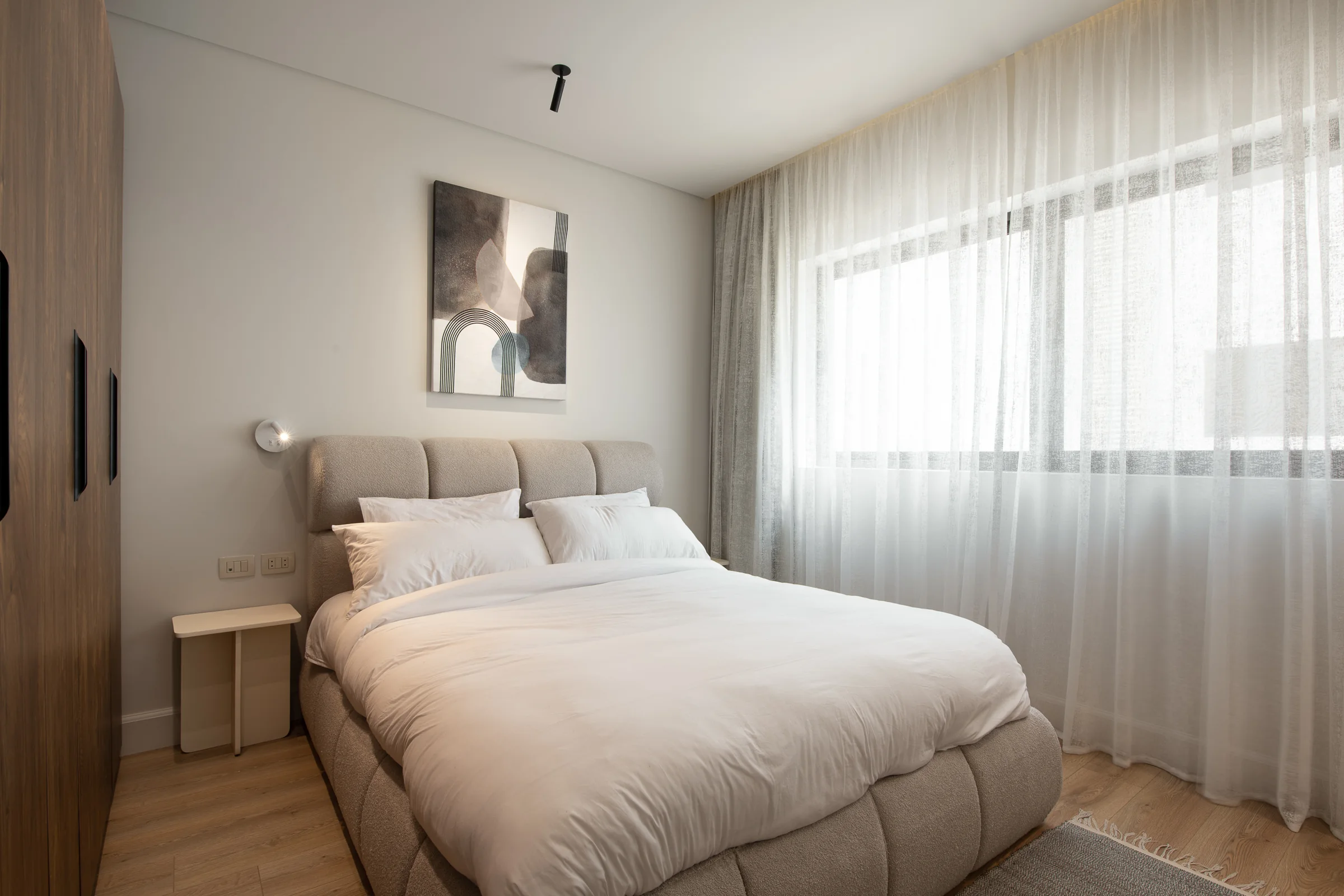 Bedroom with a low bed and curtain light across the wall.