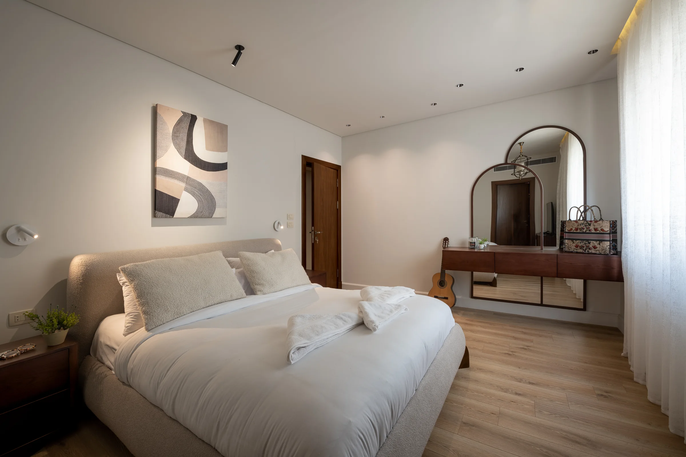 Bedroom with dressing table, arched mirror and timber floor.