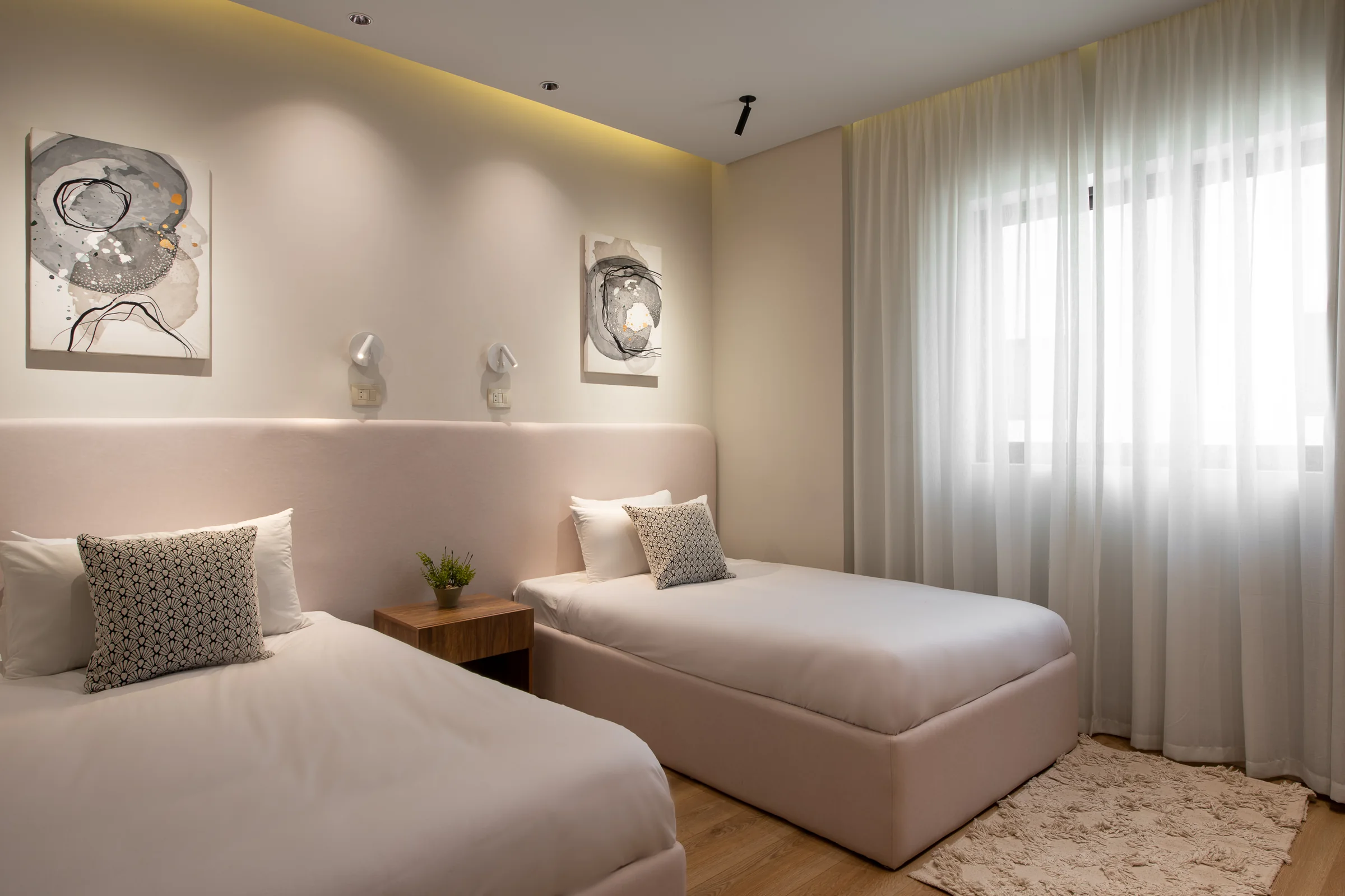 Twin bedroom with a padded headboard rail and framed works.
