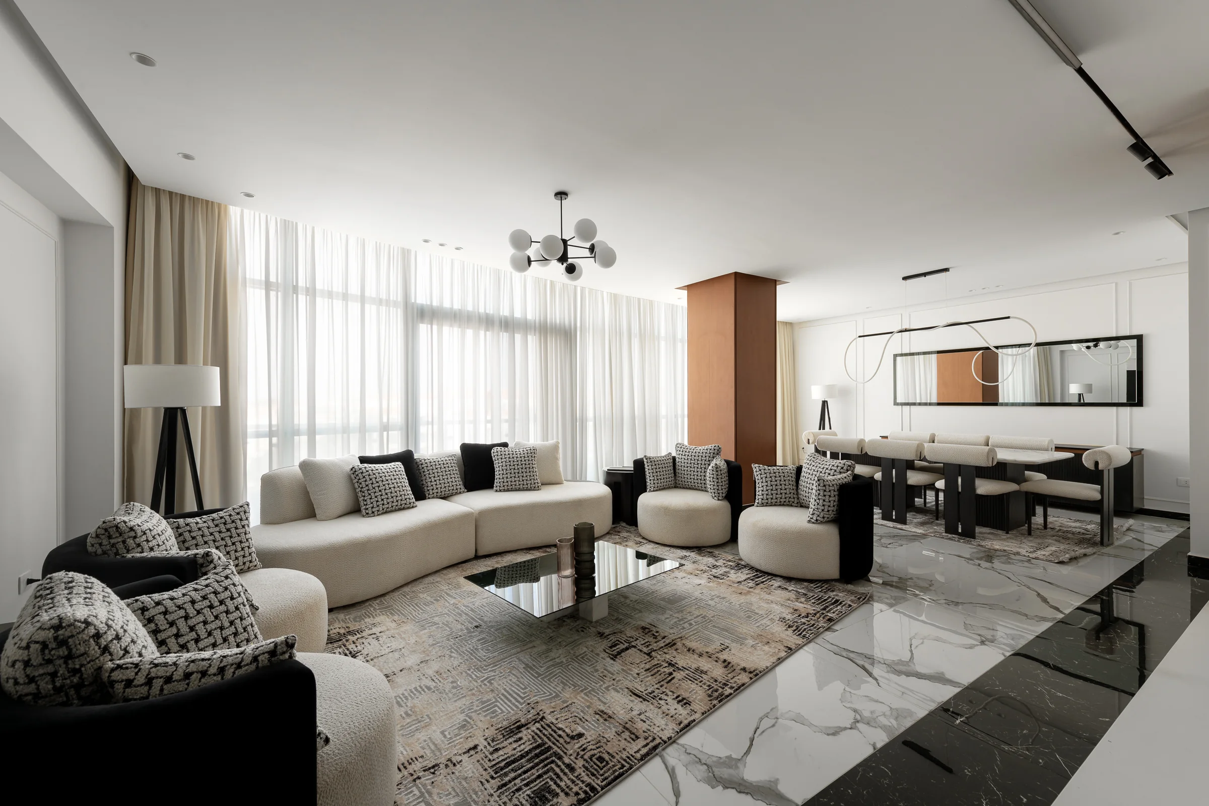 The living room wide: curved sofas, marble table, city light.