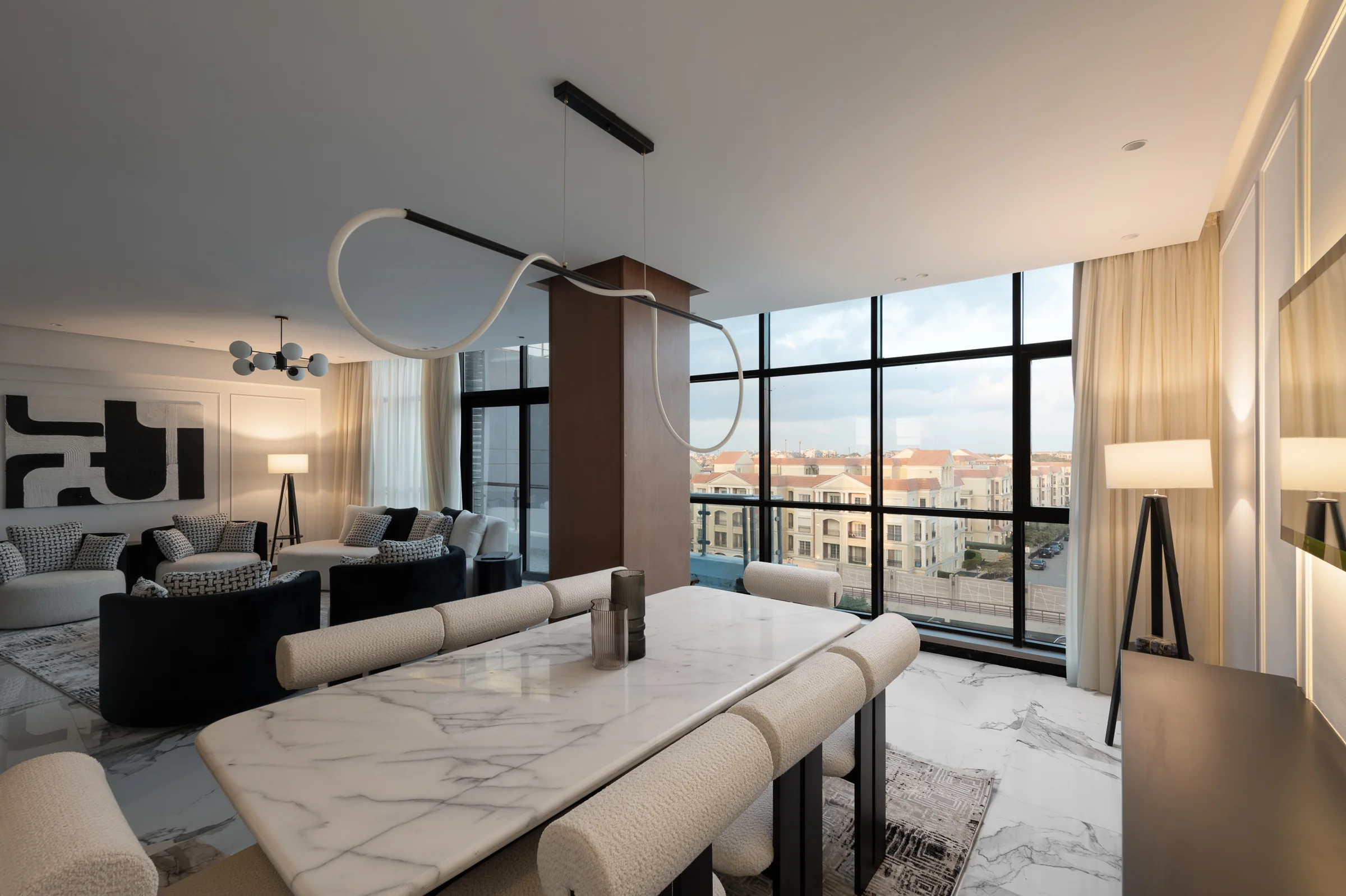 Dining table and living room with the city in the window.