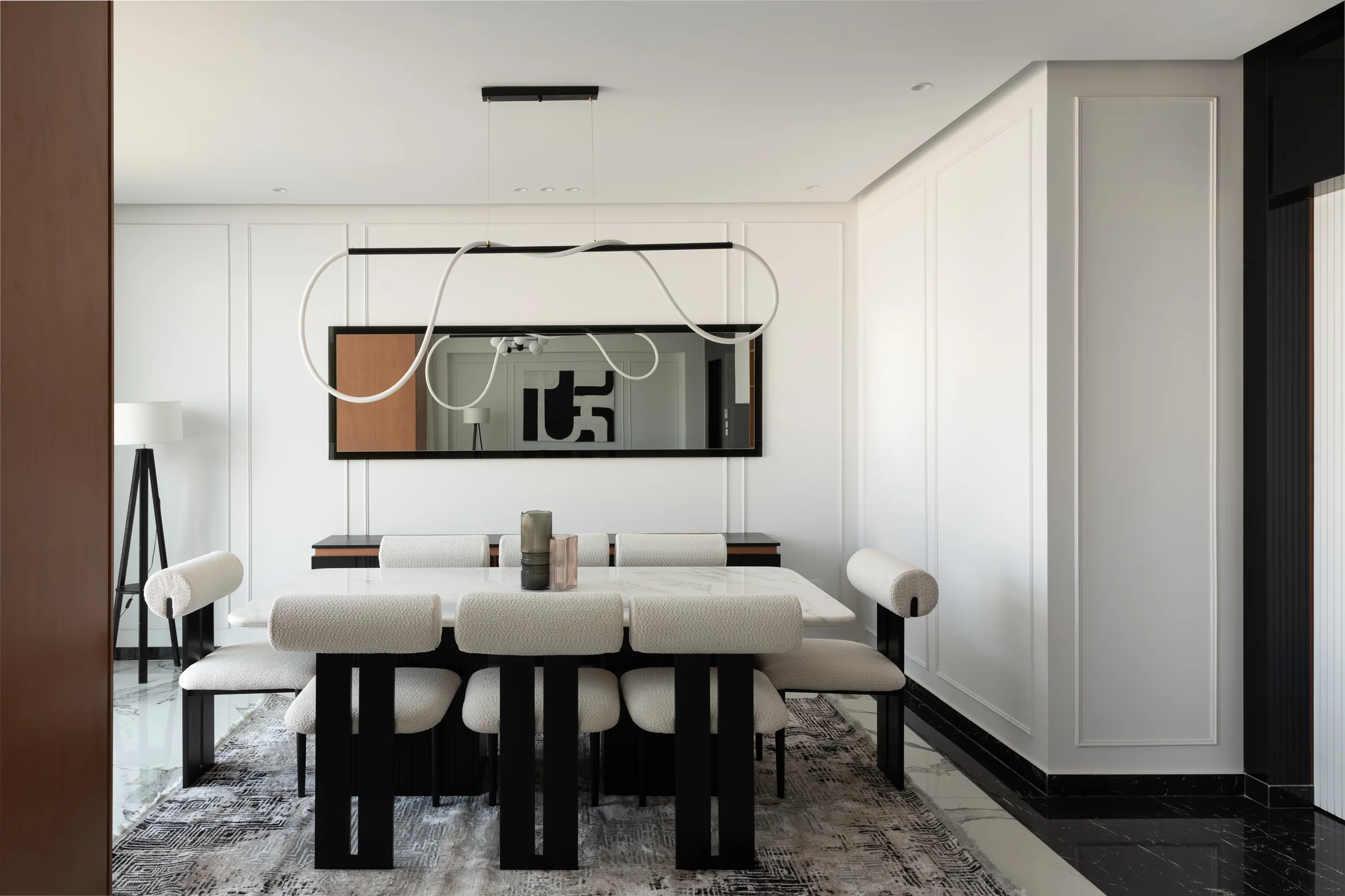 Dining table under a linear pendant, art on the end wall.