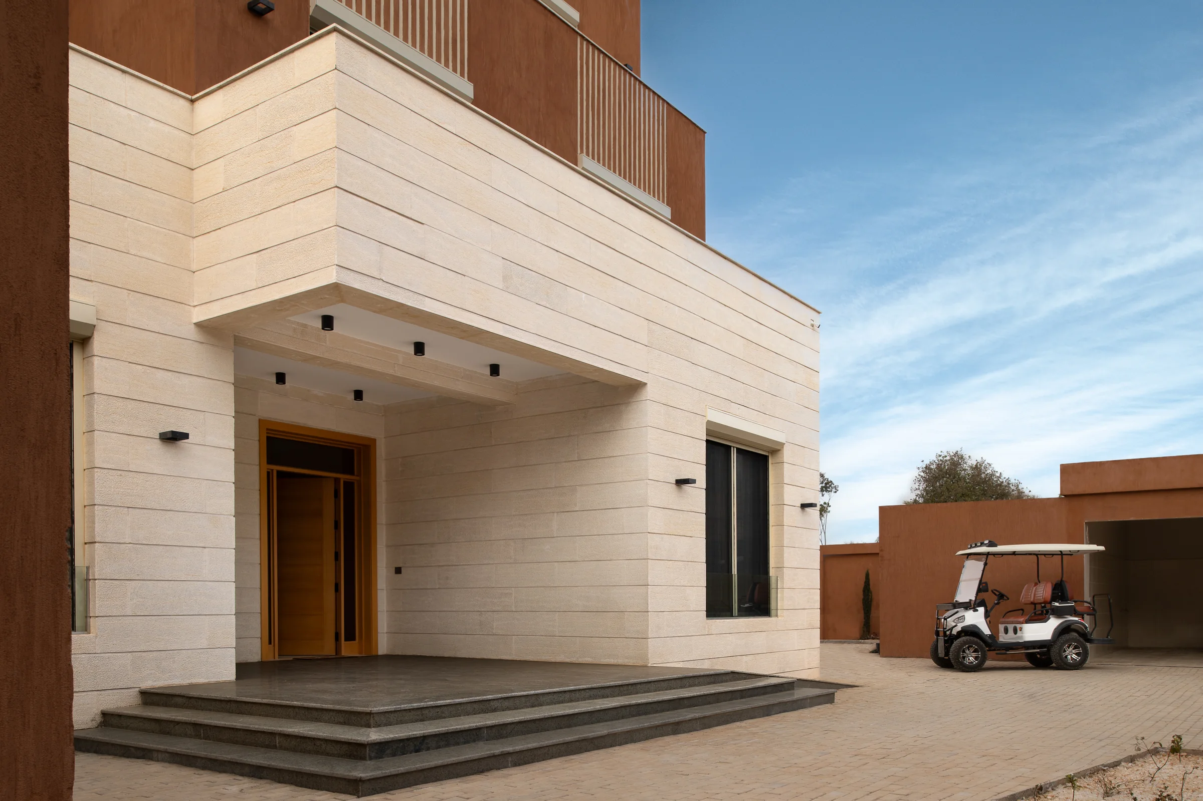 Limestone entrance porch with a deep soffit, set against a terracotta boundary wall.