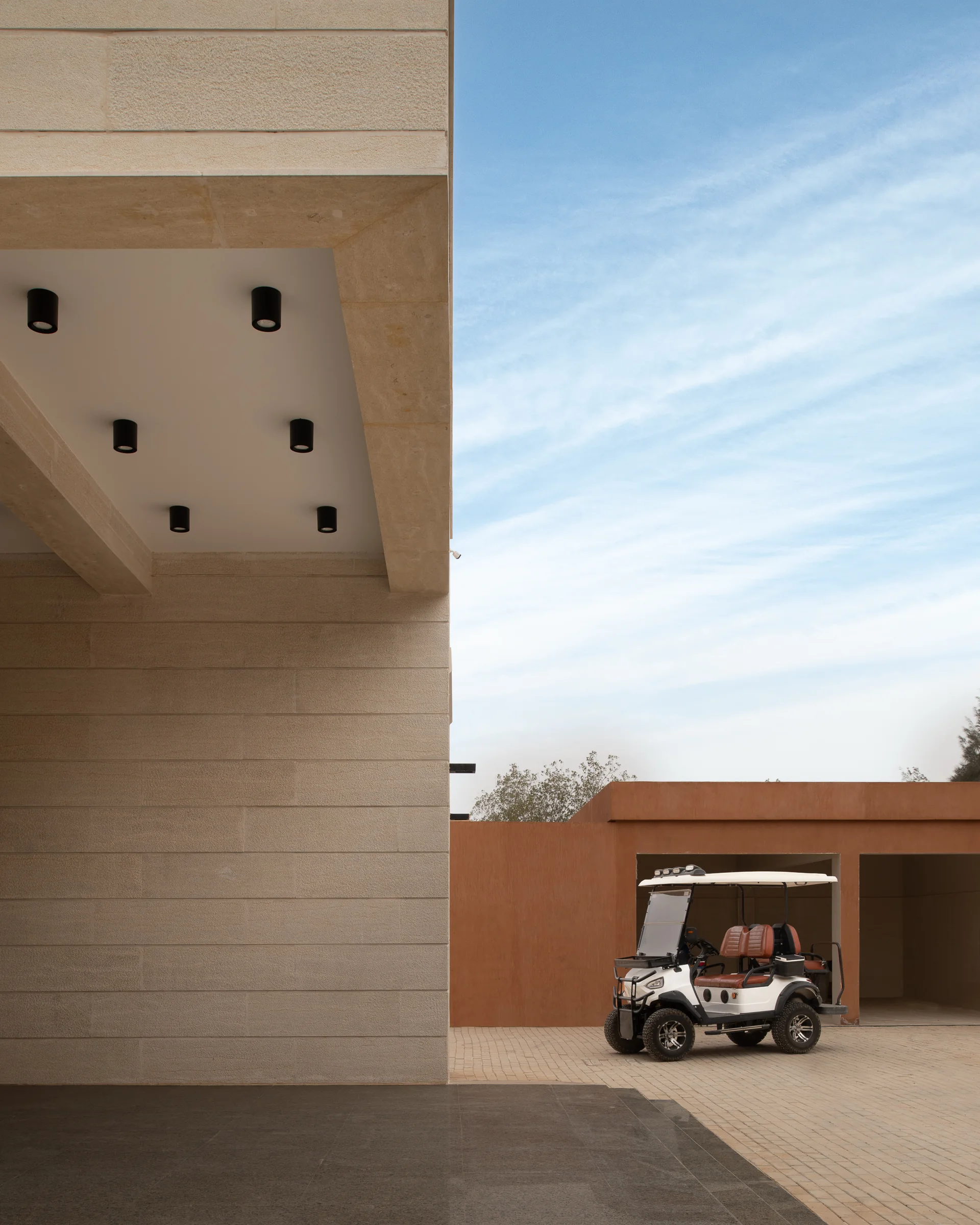 Cantilevered stone soffit and recessed downlights against open sky.