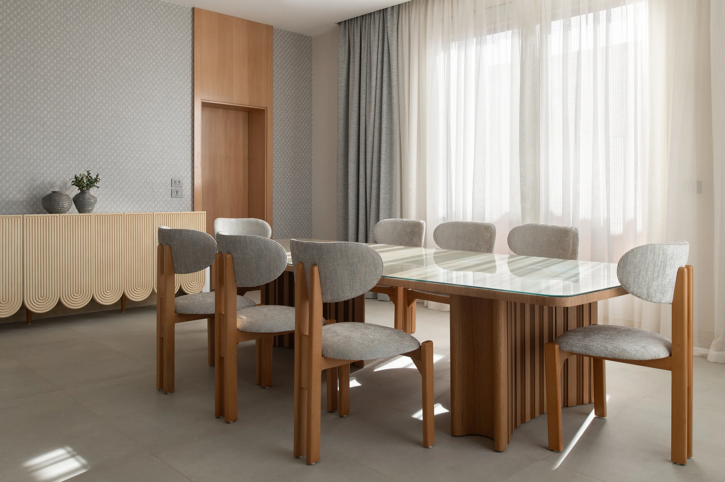 Dining room from the corner, oak chairs and a glass-topped fluted table.