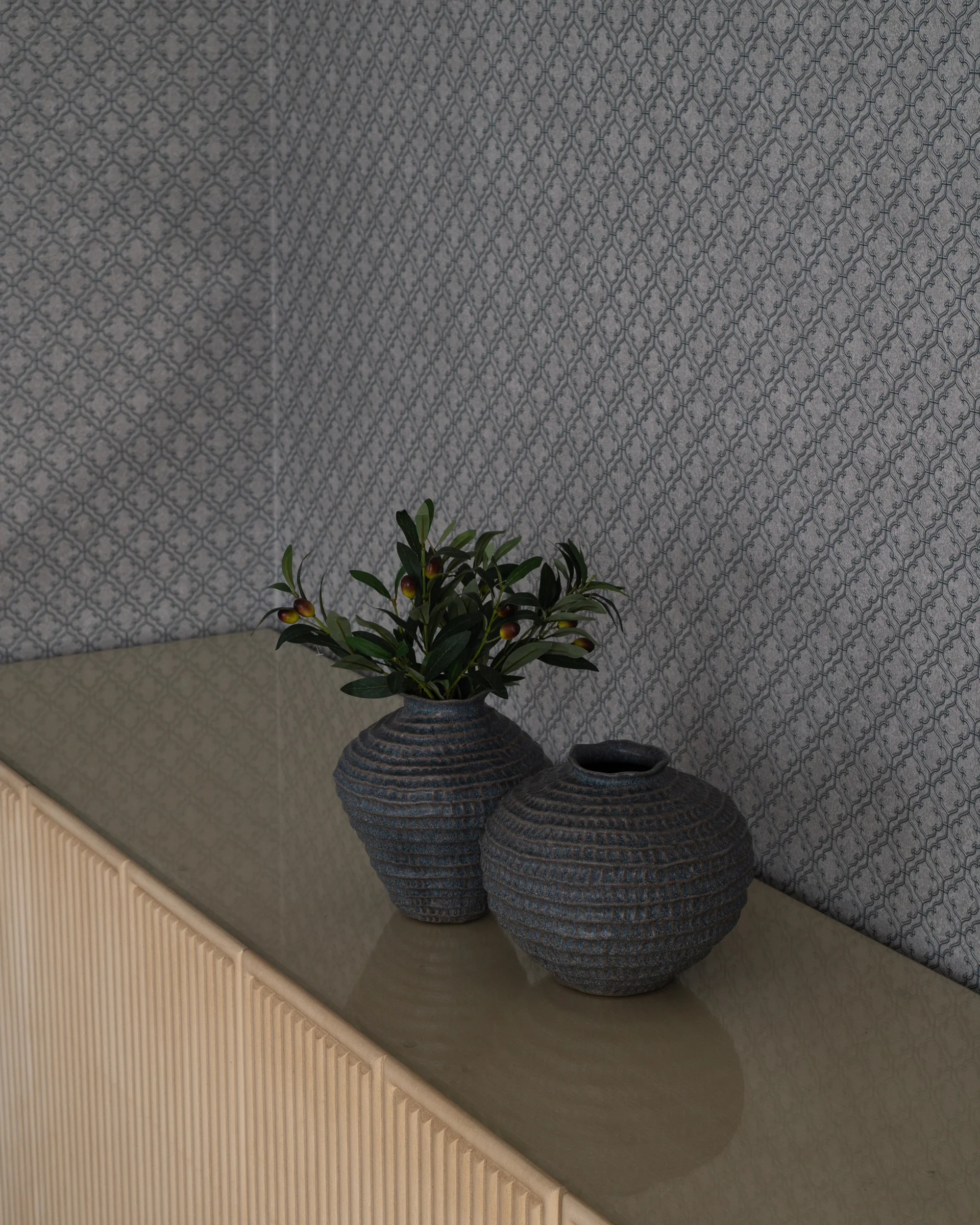 Two ceramic vases on a fluted sideboard against patterned wallpaper.