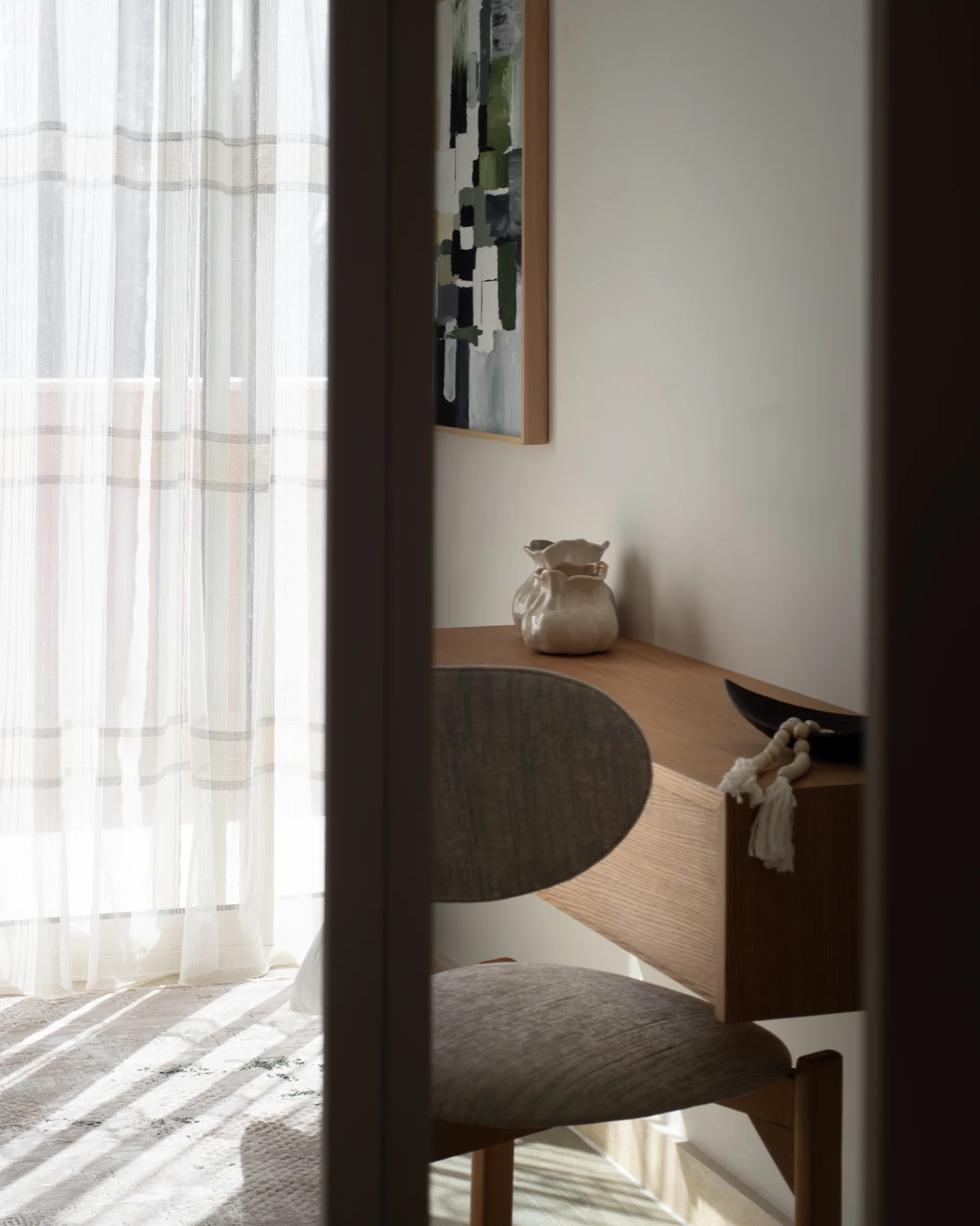 Guest room seen past a door reveal, curtain light across the floor.