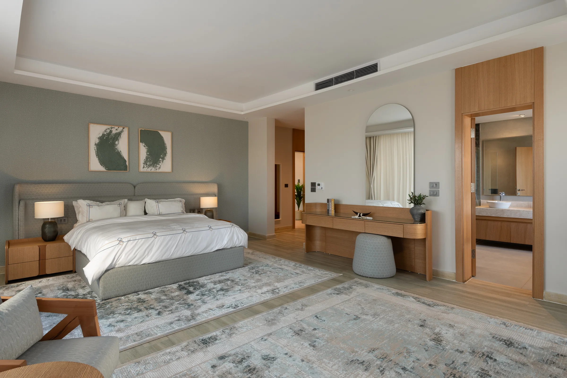 Master bedroom with dressing table, arched mirror and the bathroom beyond.