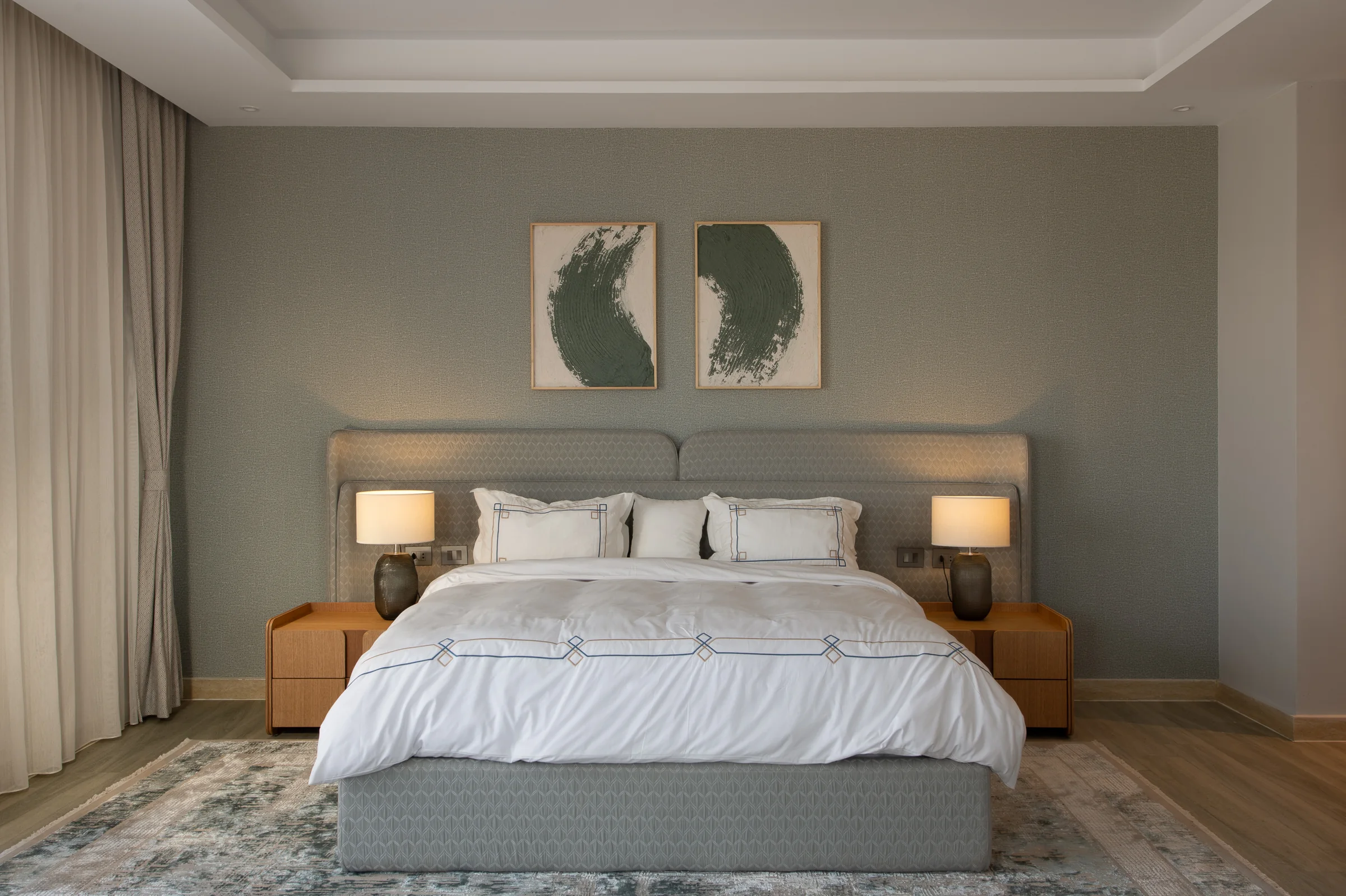 Master bed against a sage headboard wall, twin lamps lit.