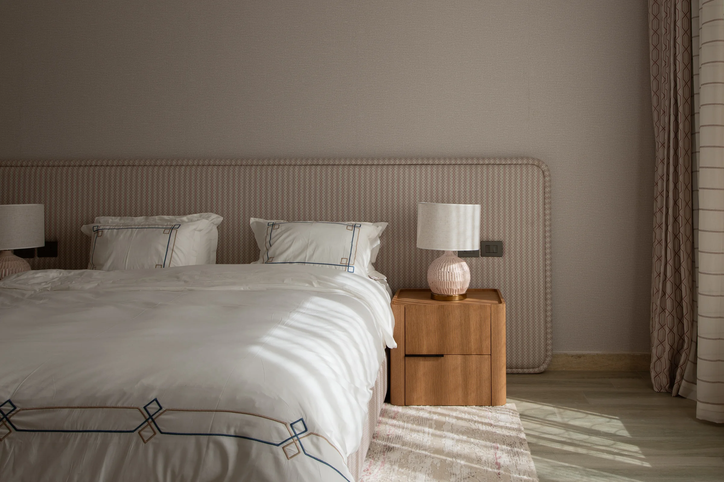 Bed and bedside table with light raking across the linen.