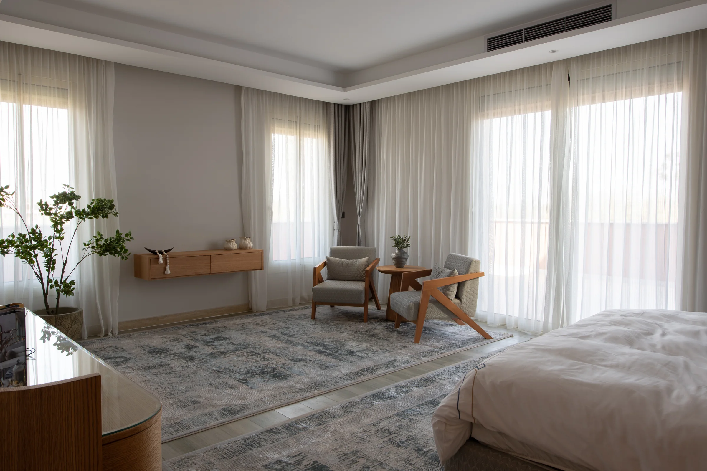 Bedroom with a seating corner and floor-to-ceiling sheer curtains.