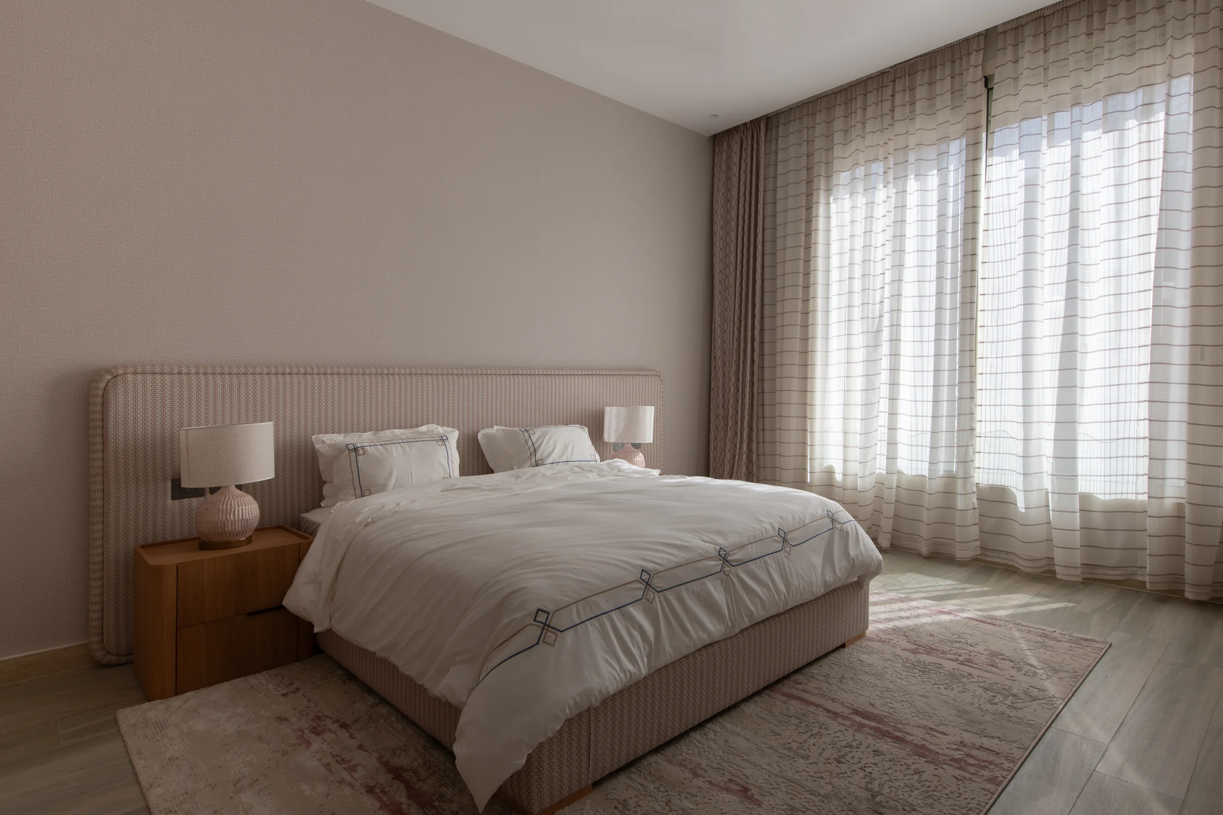 Guest bedroom with a wide window wall and layered rugs.