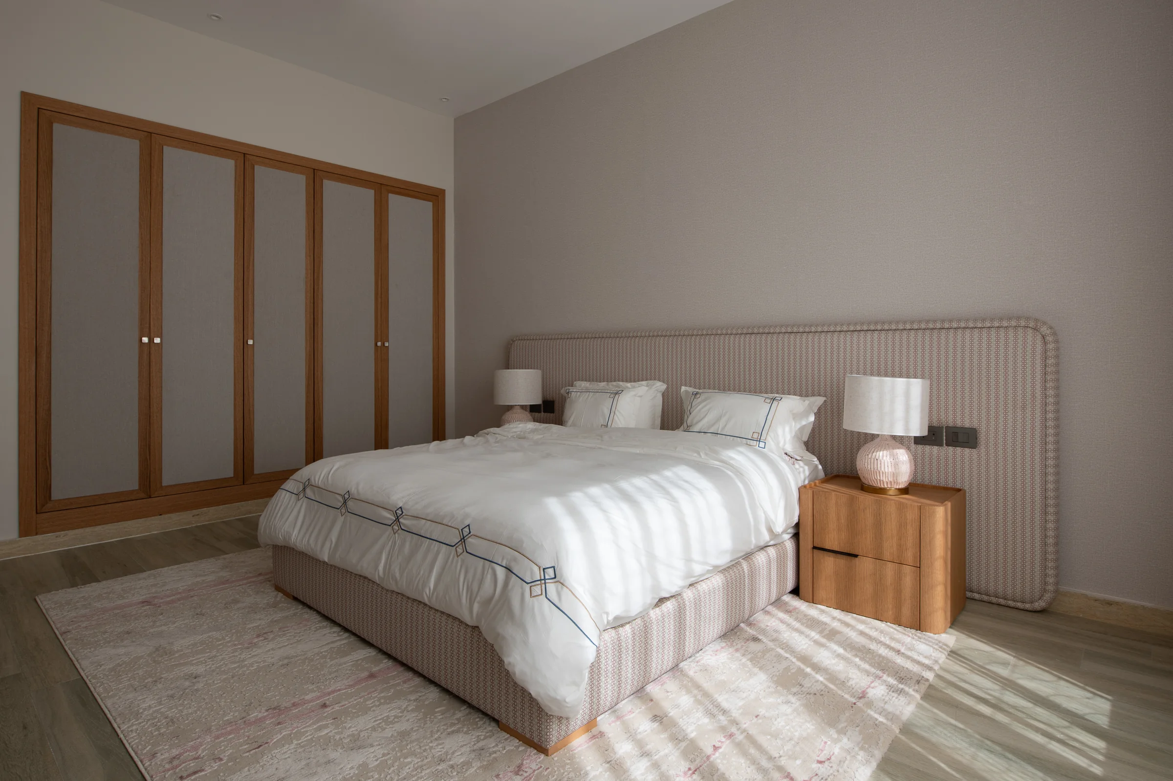 Guest bedroom with fitted oak wardrobes and a fluted headboard.