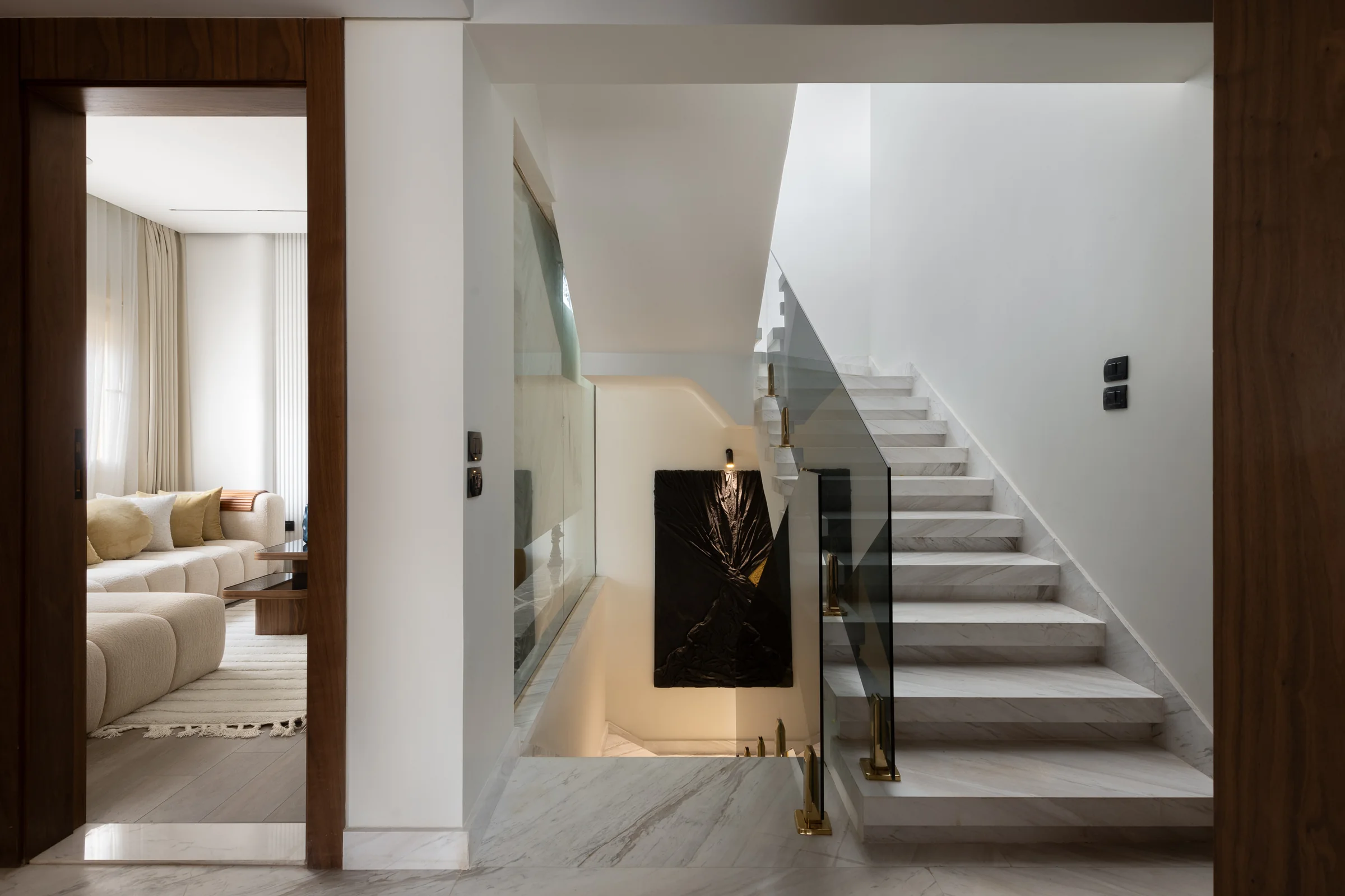 Stair hall with a white column and a glass balustrade.