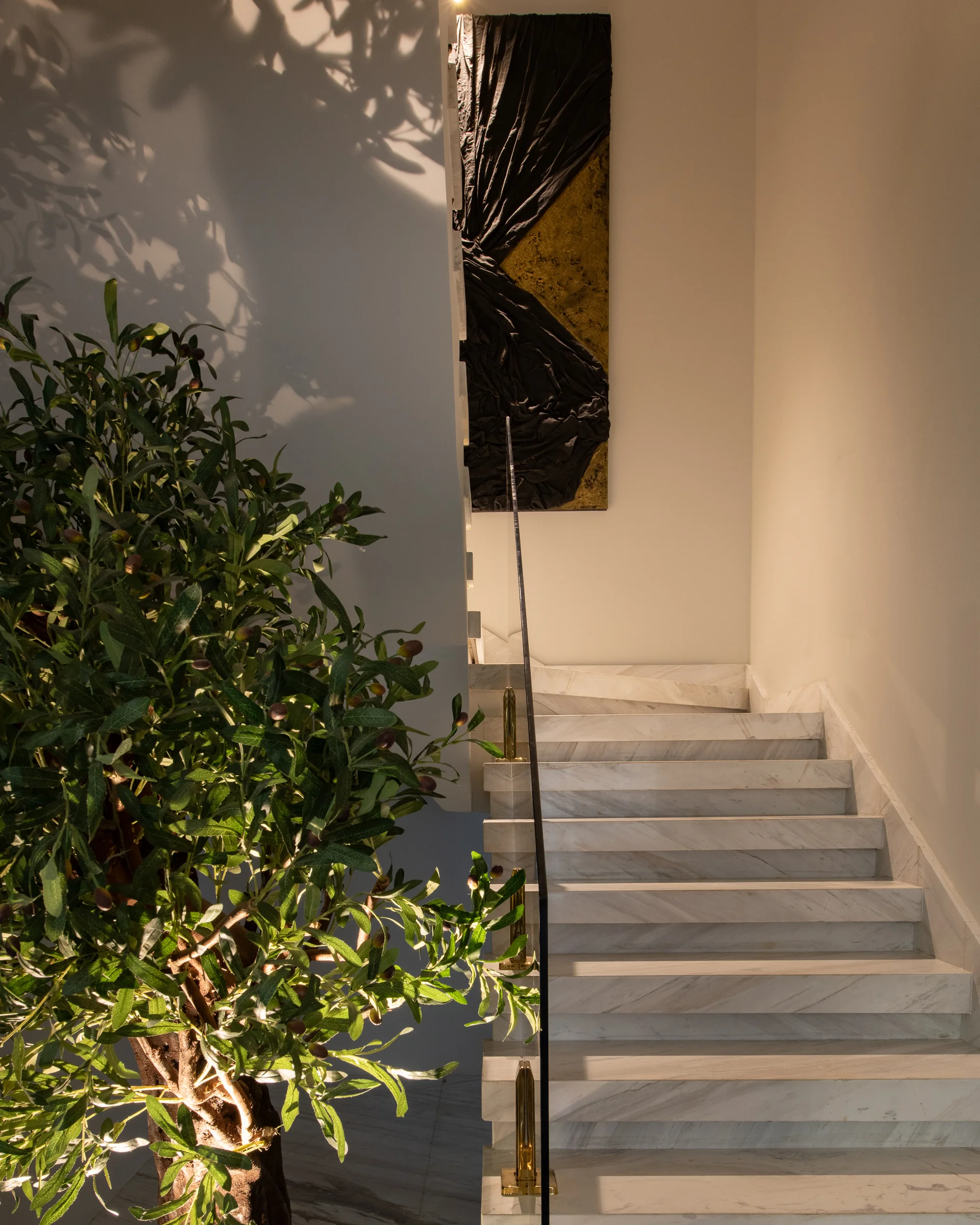 Olive branches against the stair wall and framed artwork.