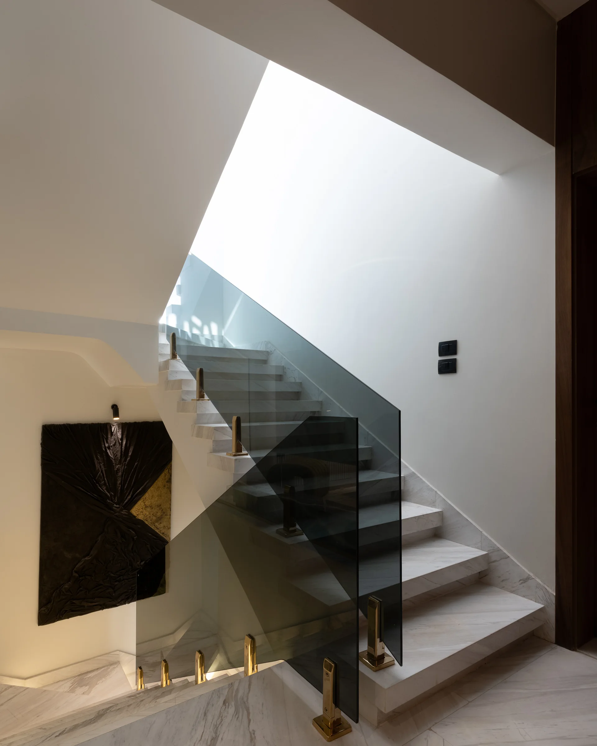 Stair under the skylight, brass uplights along the tread edge.